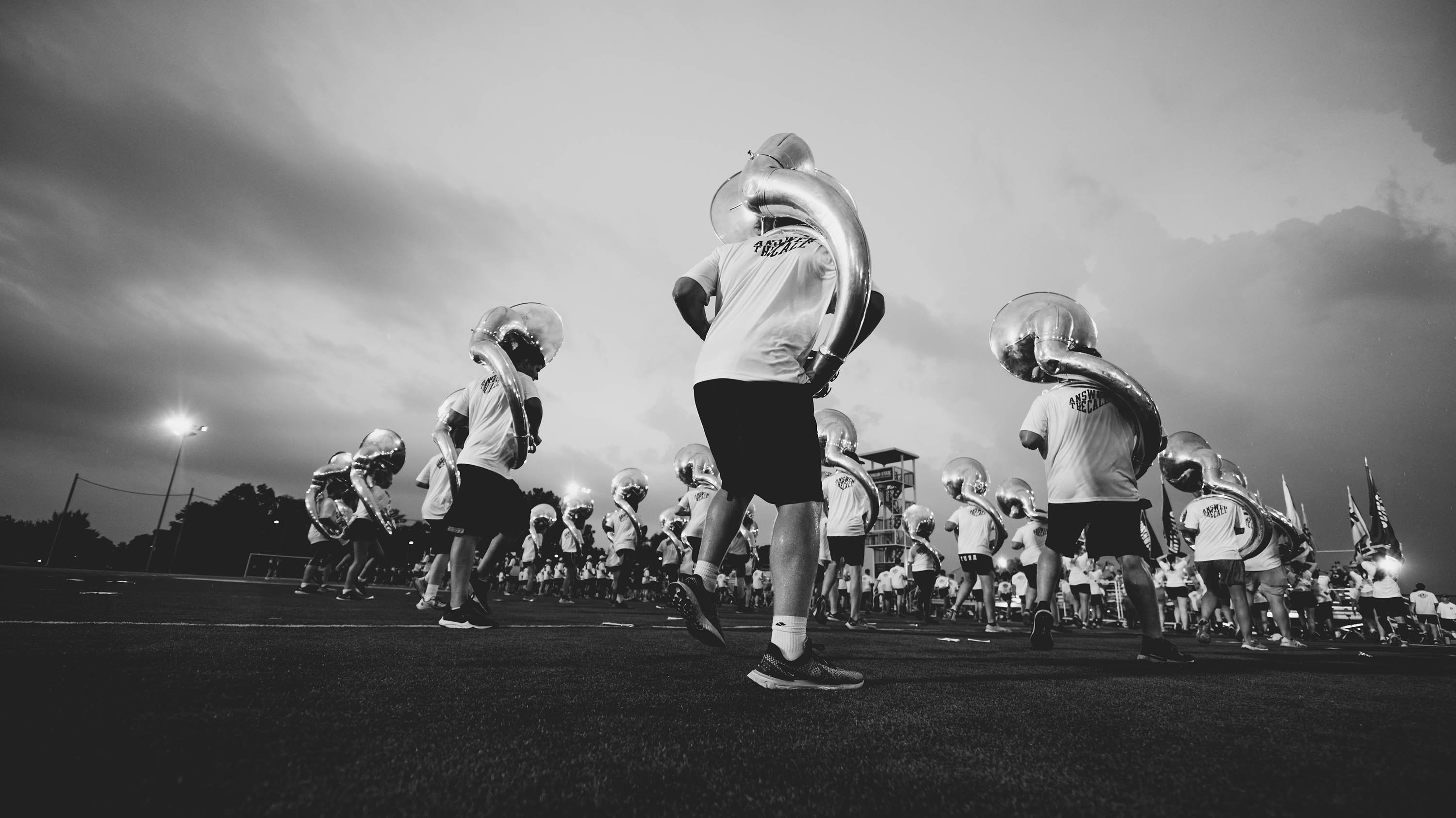 Black and white image of tuba players on practice field