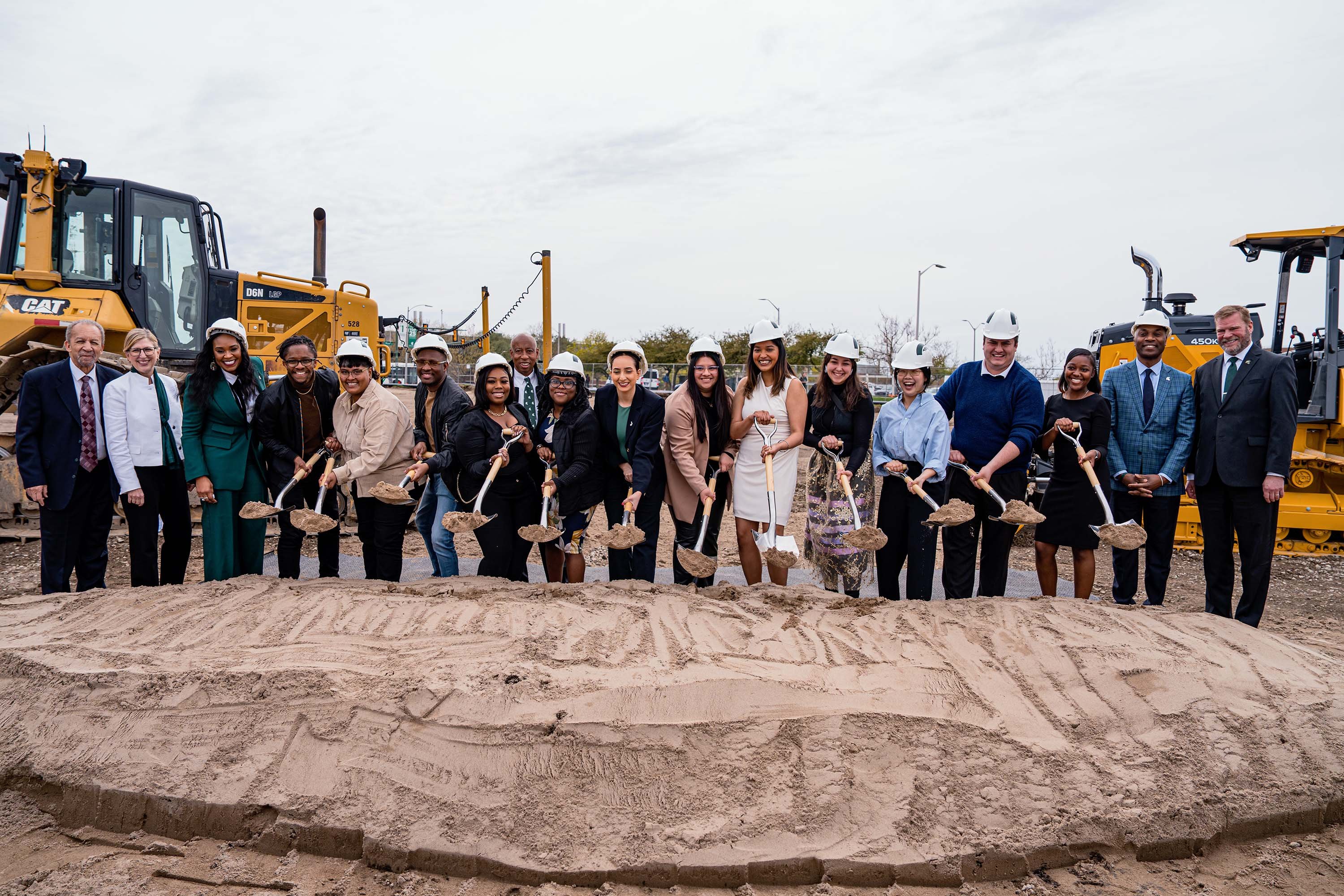 From left to right, Lee June, Interim President Teresa Woodruff, Rema Vassar, Mario Lemons, Lesly Morales, Dante Booker, Sharron Reed-Davis, Vennie Gore, Miracle Chatman, Sarah McConville, Tammi Cervantes, Shiksha Sneha, Neely Bardwell, Sujin Lee, George Ramirez-Madrigal, Drue Bender, Jabbar Bennett and Thomas Jeitschko hold shovels at the multicultural center groundbreaking at MSU. Photo by Nick Schrader.