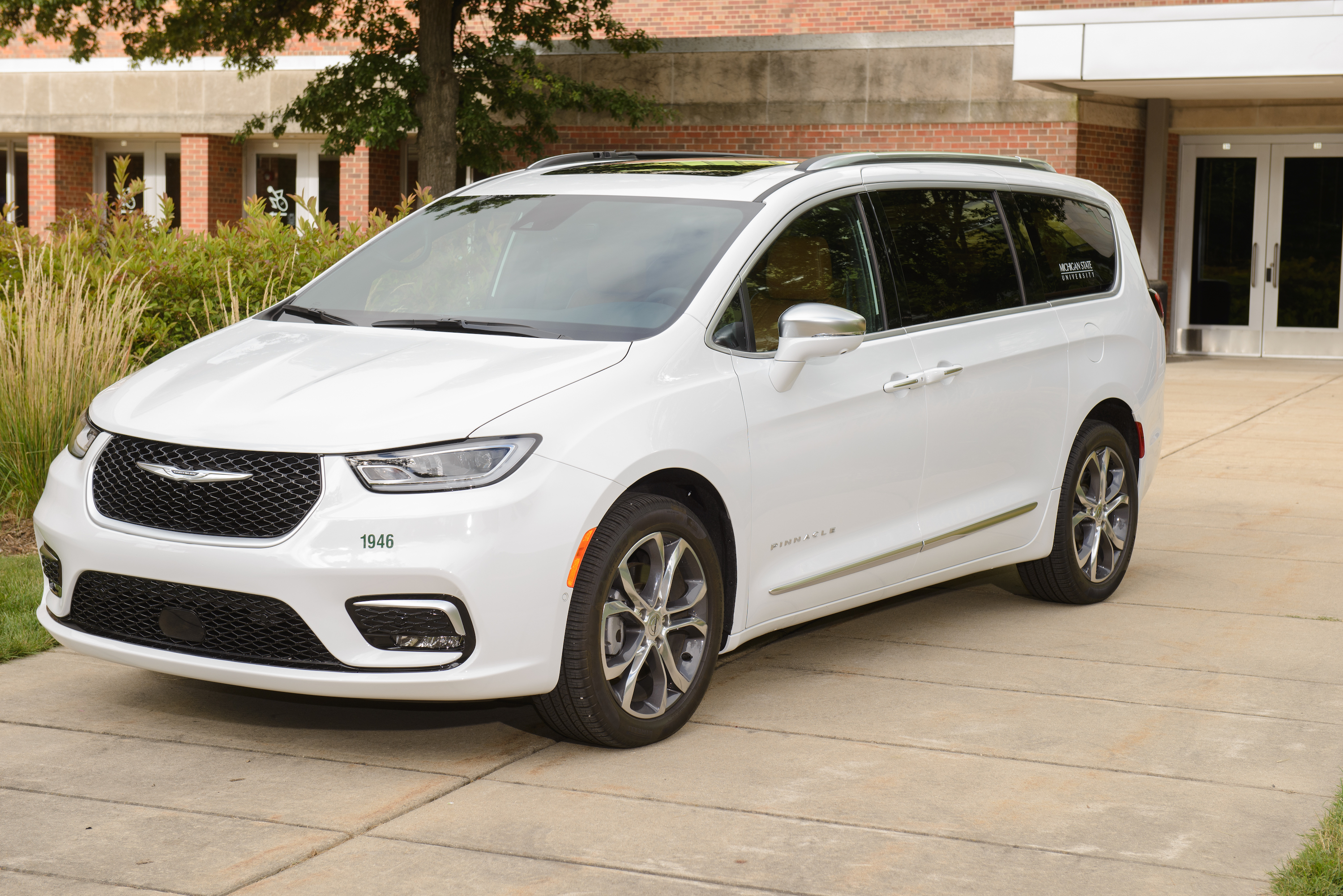 White Chrysler Pacifica van on the sidewalk in front of Wells Hall.