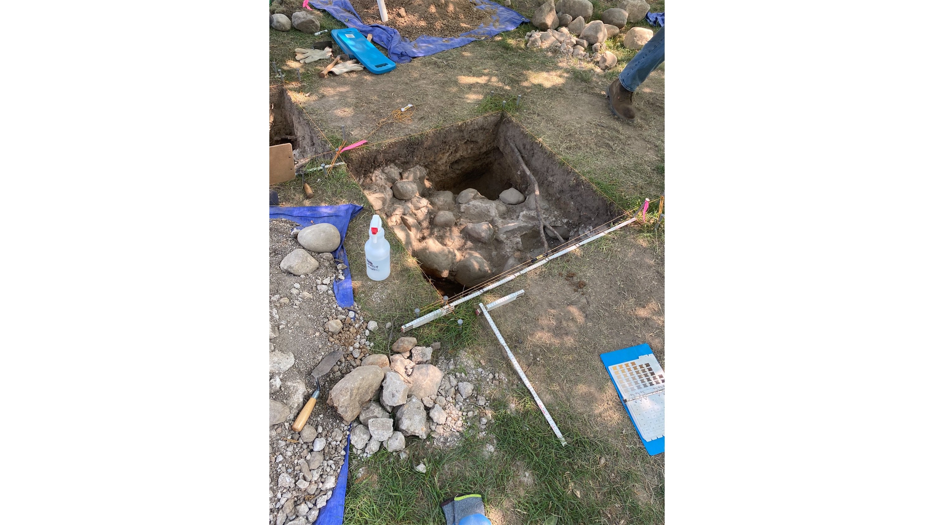 A rock and cement foundation in square hole dug in the ground