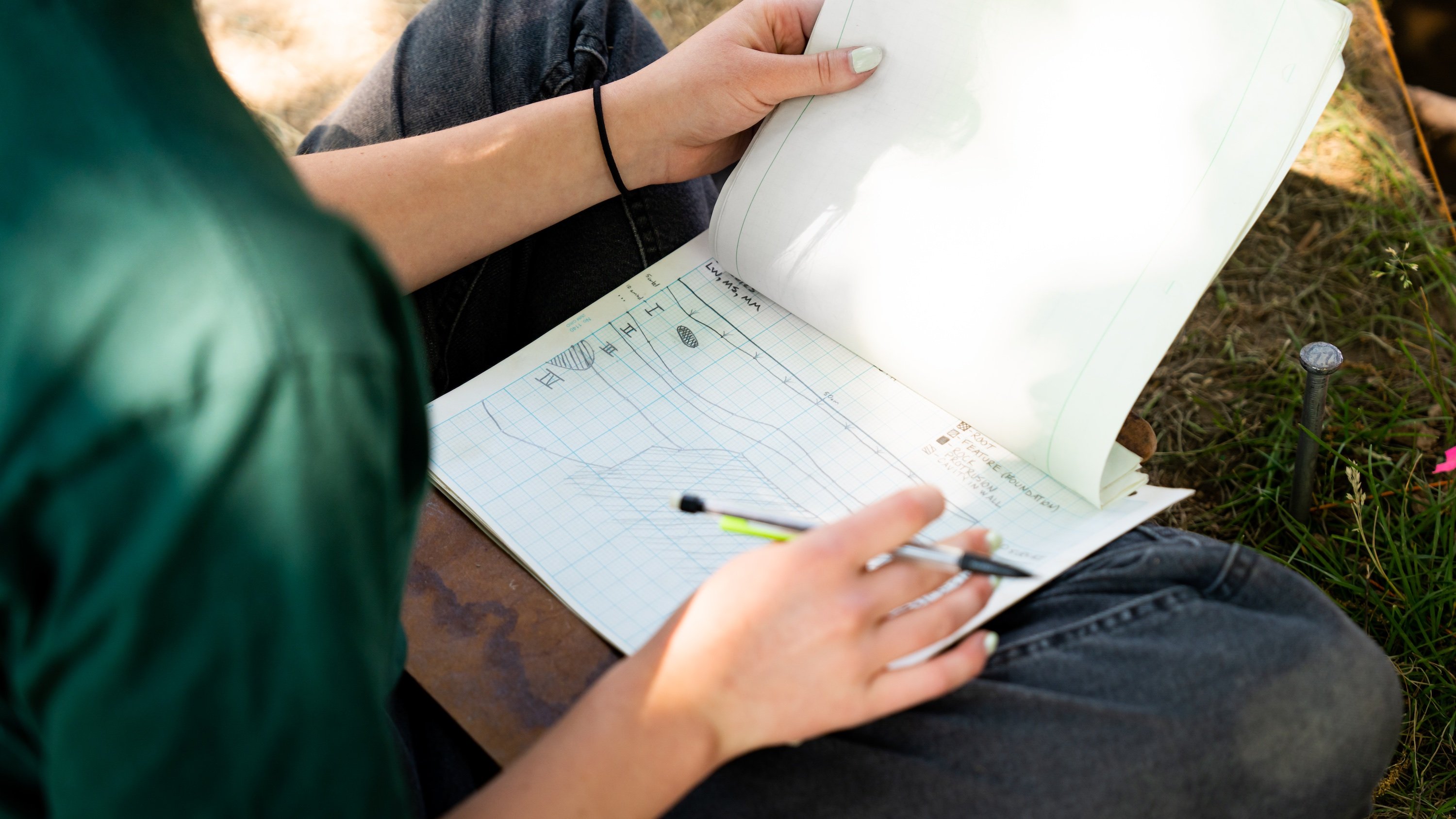 A person draws horizontal lines on grid paper.