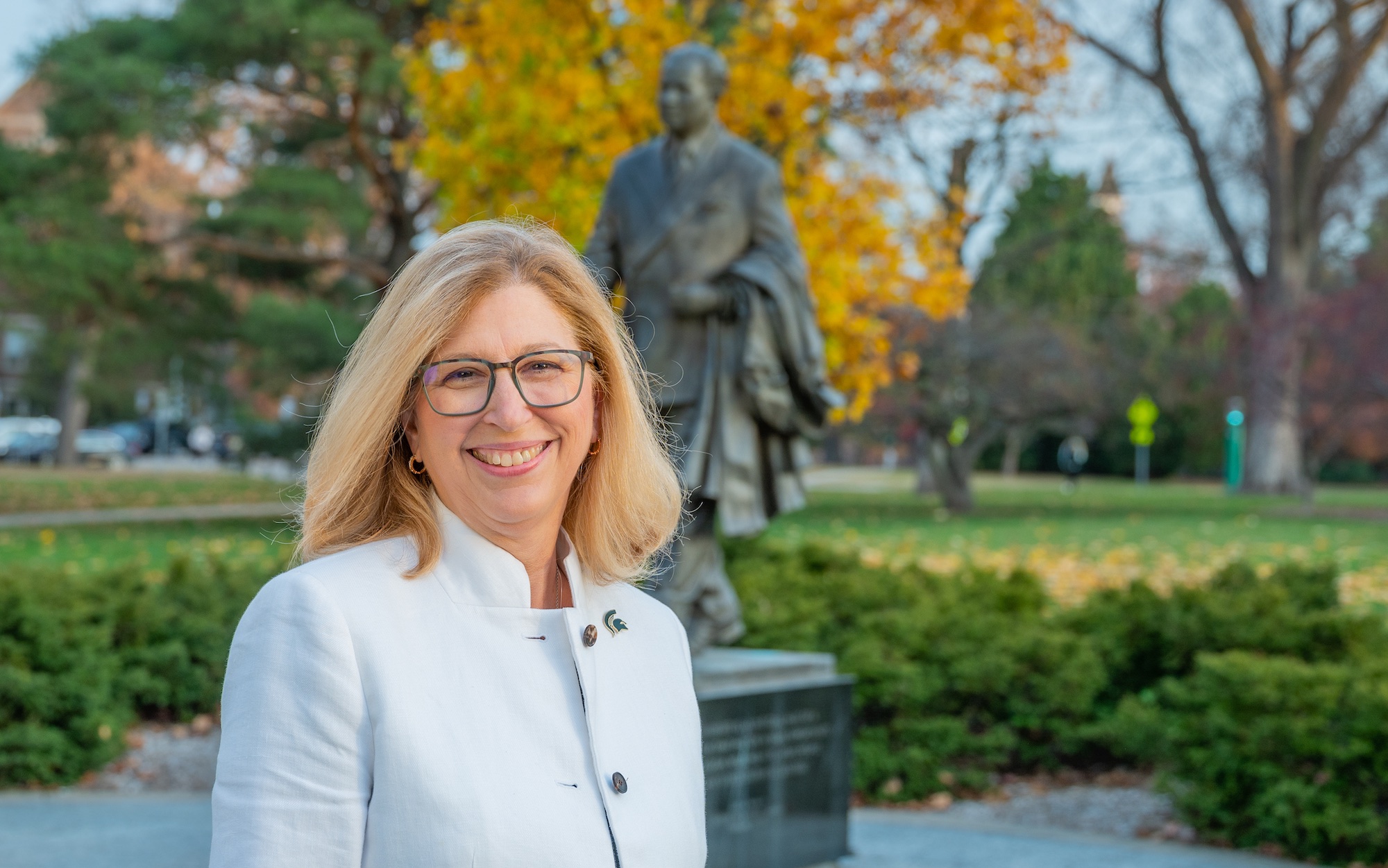 Teresa K. Woodruff, Ph.D., in front of the John A. Hannah statue on MSU's campus