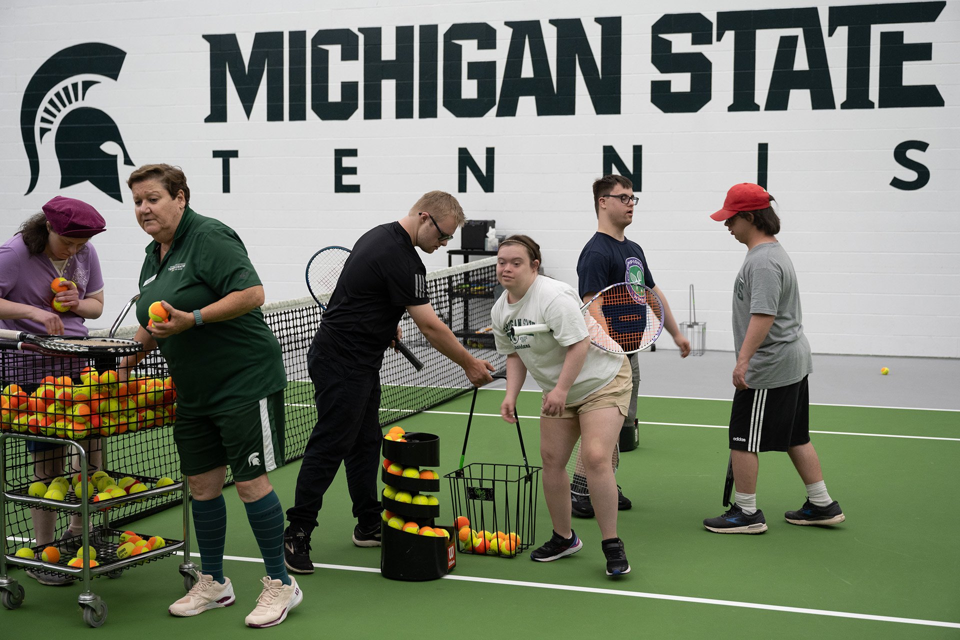 participants in motion as they gather tennis rackets and balls to get ready to play