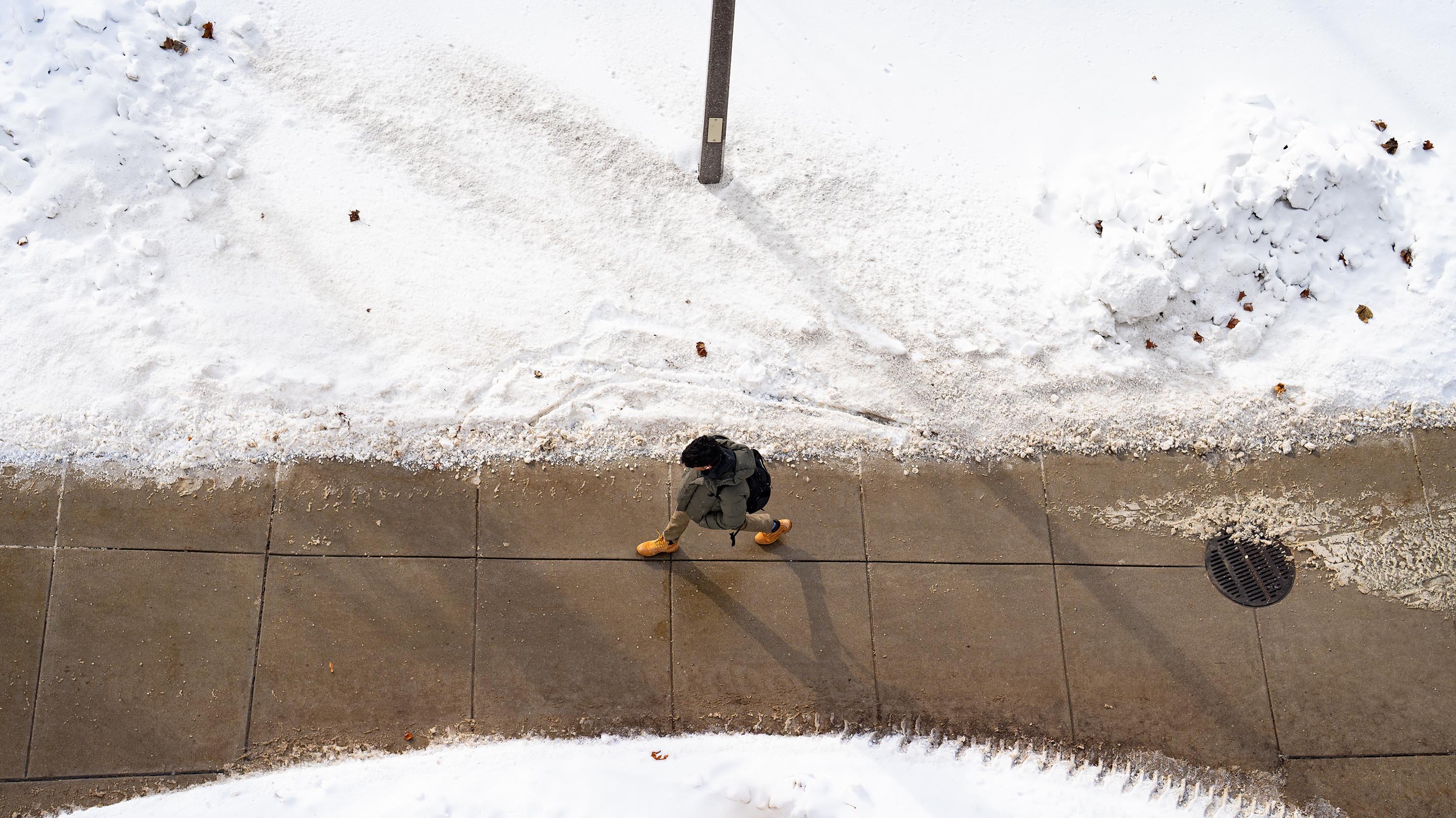 Bird's eye view of student walking on sidewalk on snowy day