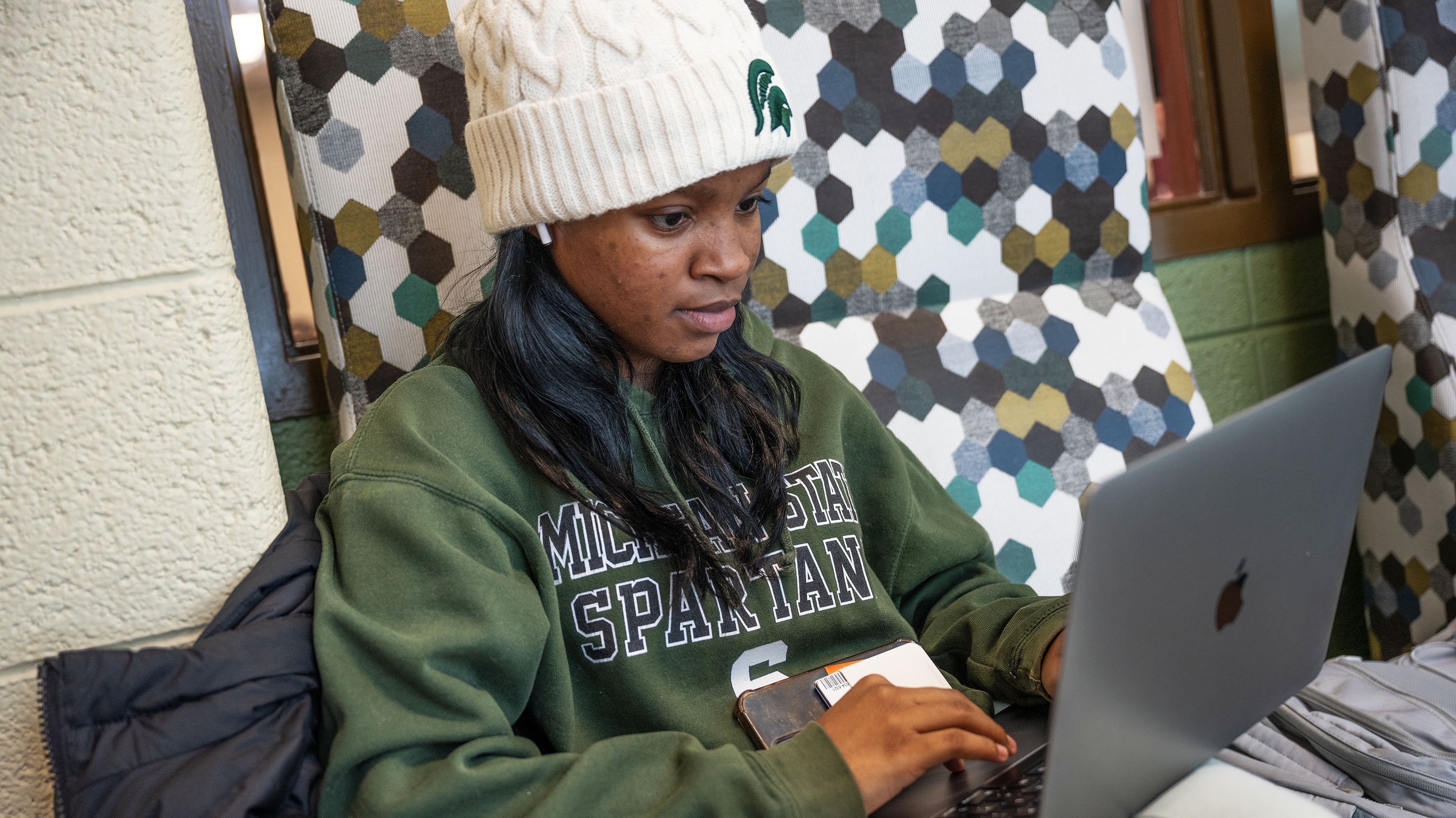 Student in MSU hat and sweatshirt studying