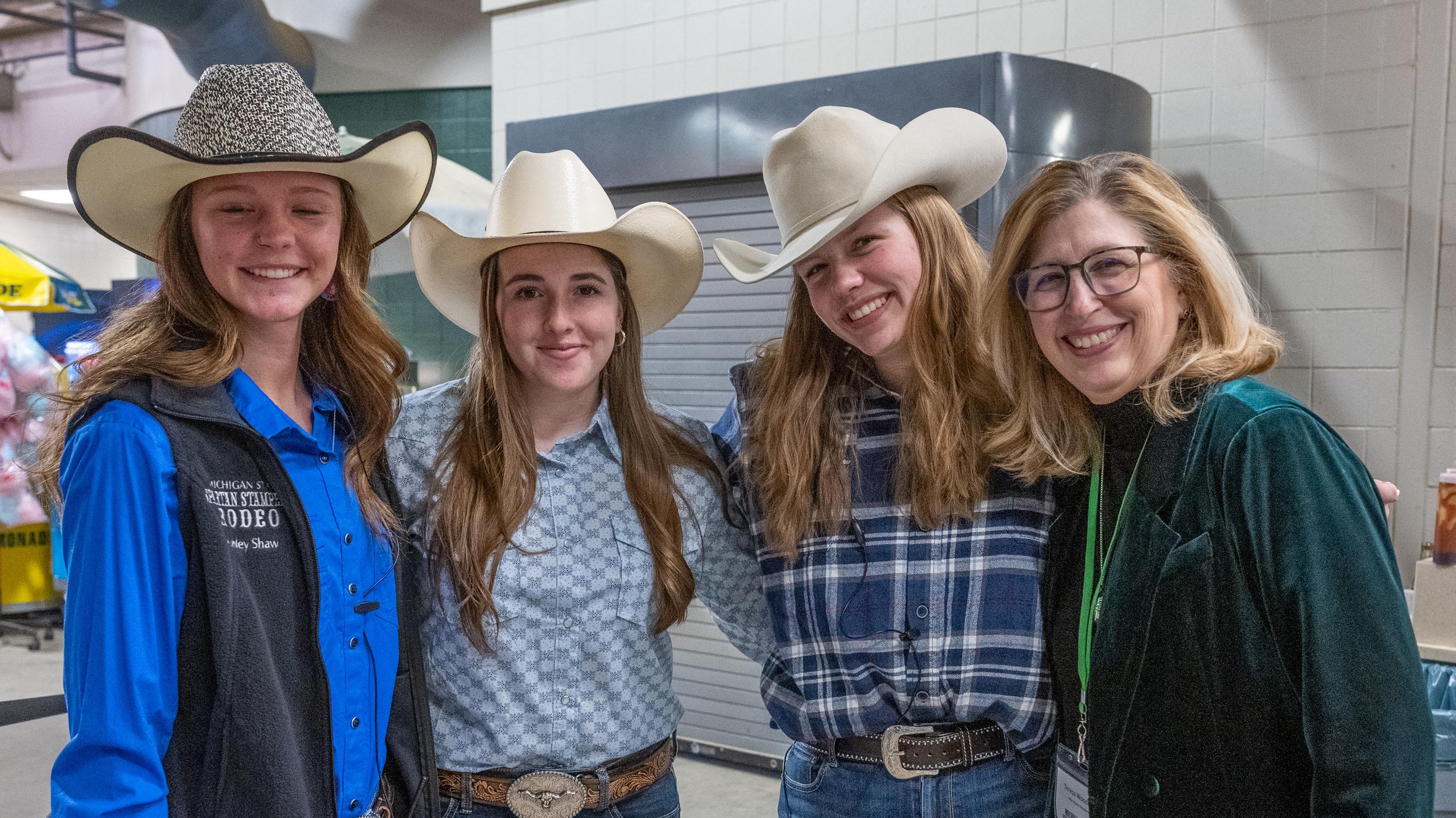 People in cowboy hats and Theresa Woodruff at rodeo