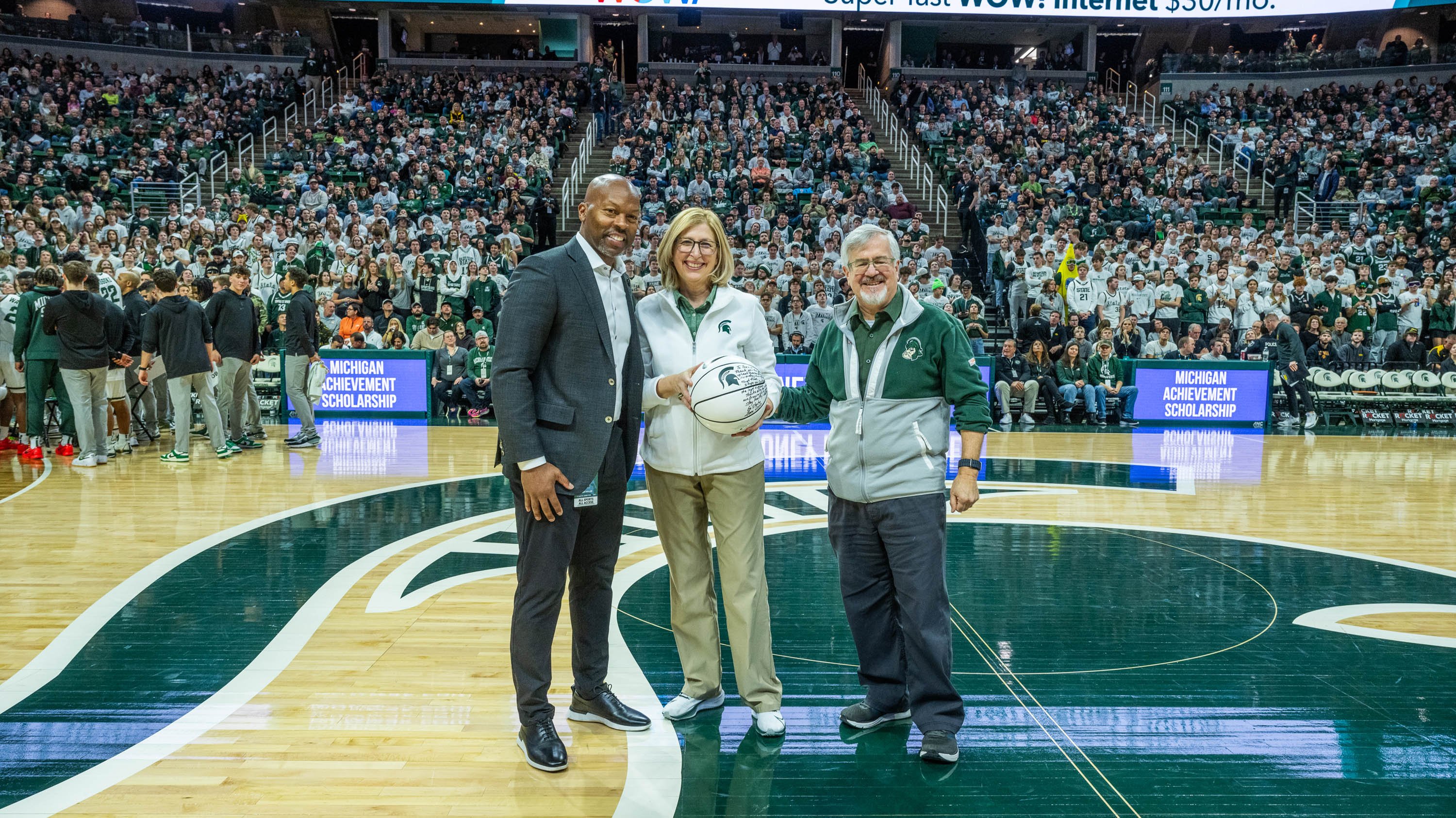 Allan Haller, Theresa K. Woodruff and Tom O'Halloran on basketball court with signed ball
