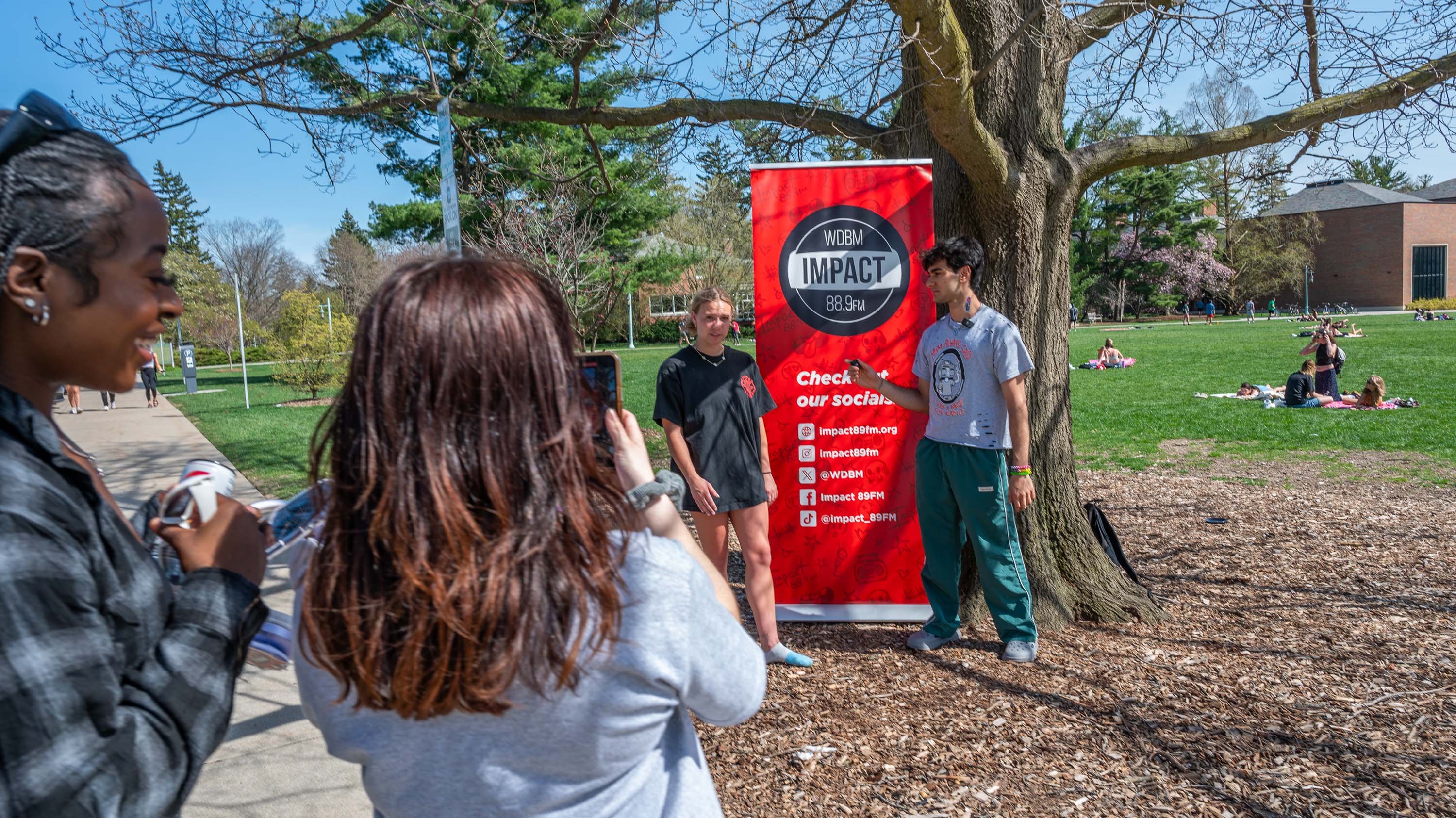 Impact FM staff filming and interviewing a student