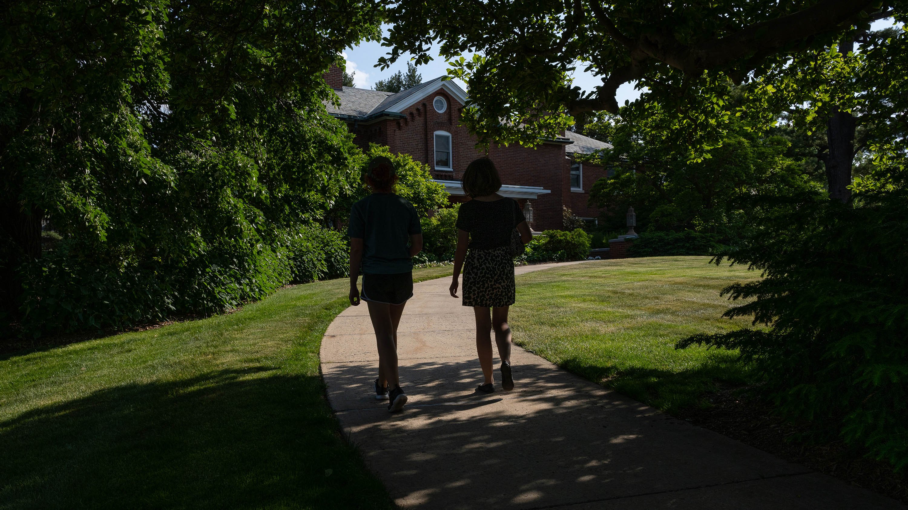 People walking through shadowed path in front of Cowles House