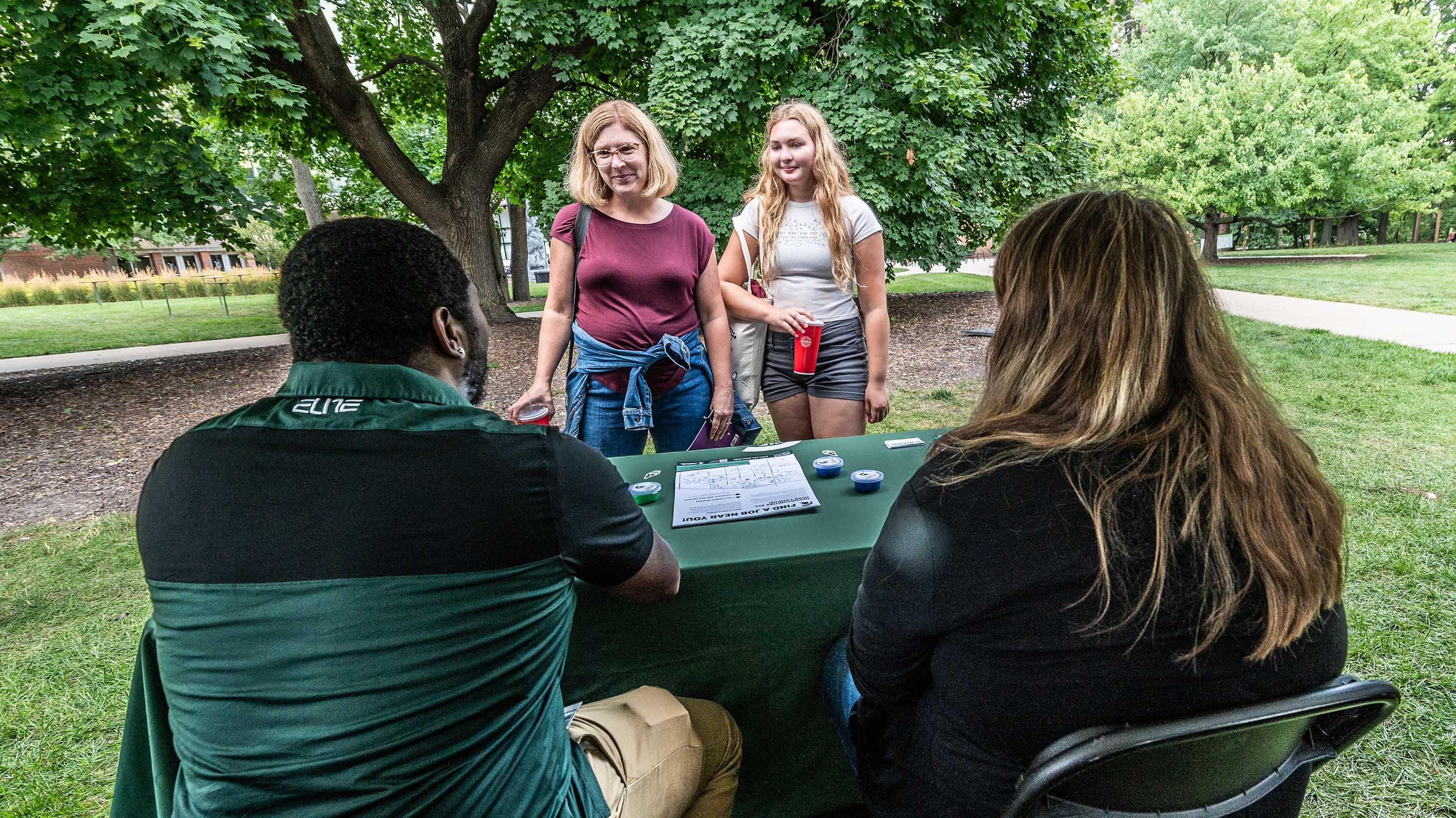Student andparent visiting a table at Green and White Day
