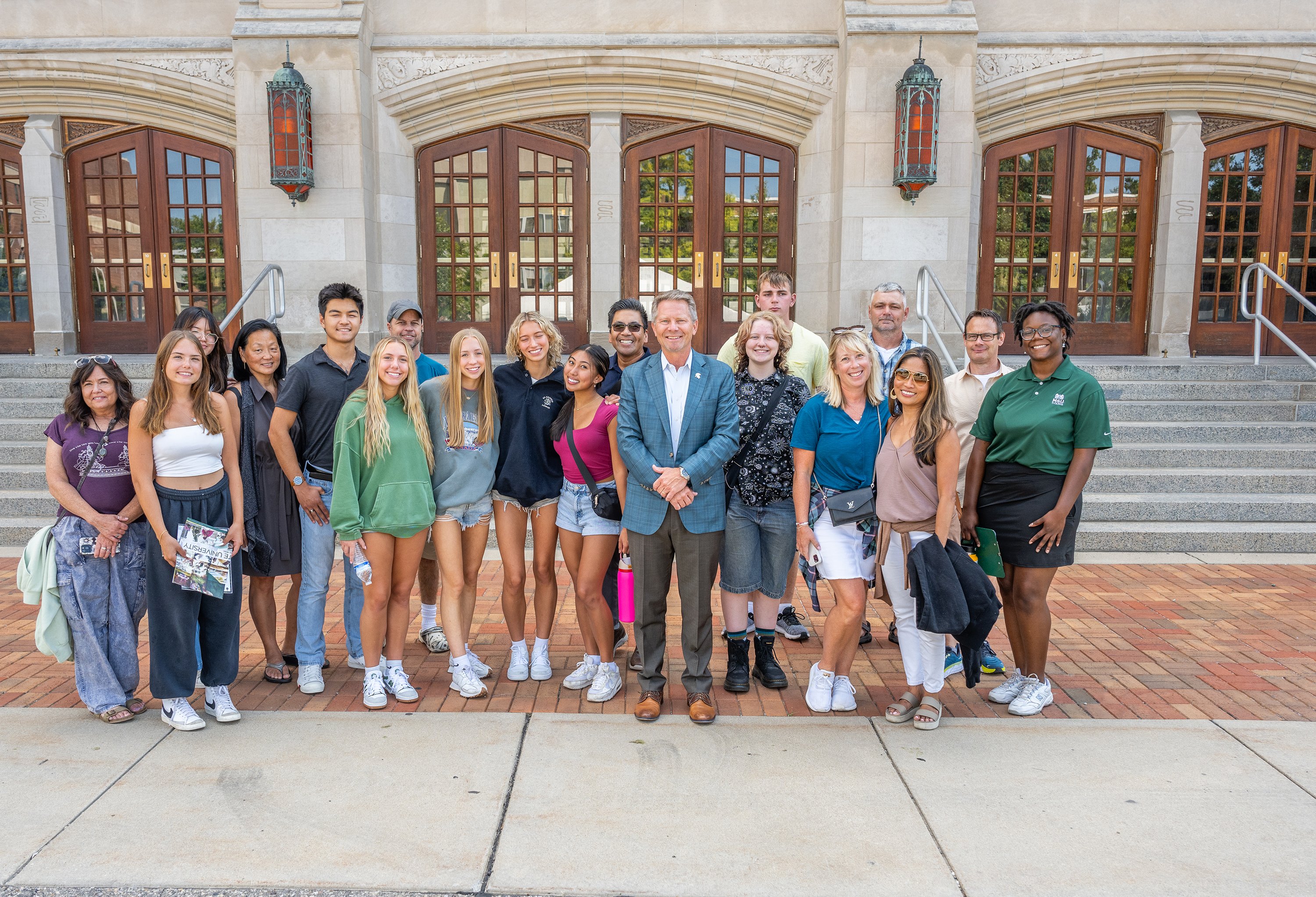 President Kevin Guskiewicz poses with a group of individuals outside of the Auditorium.