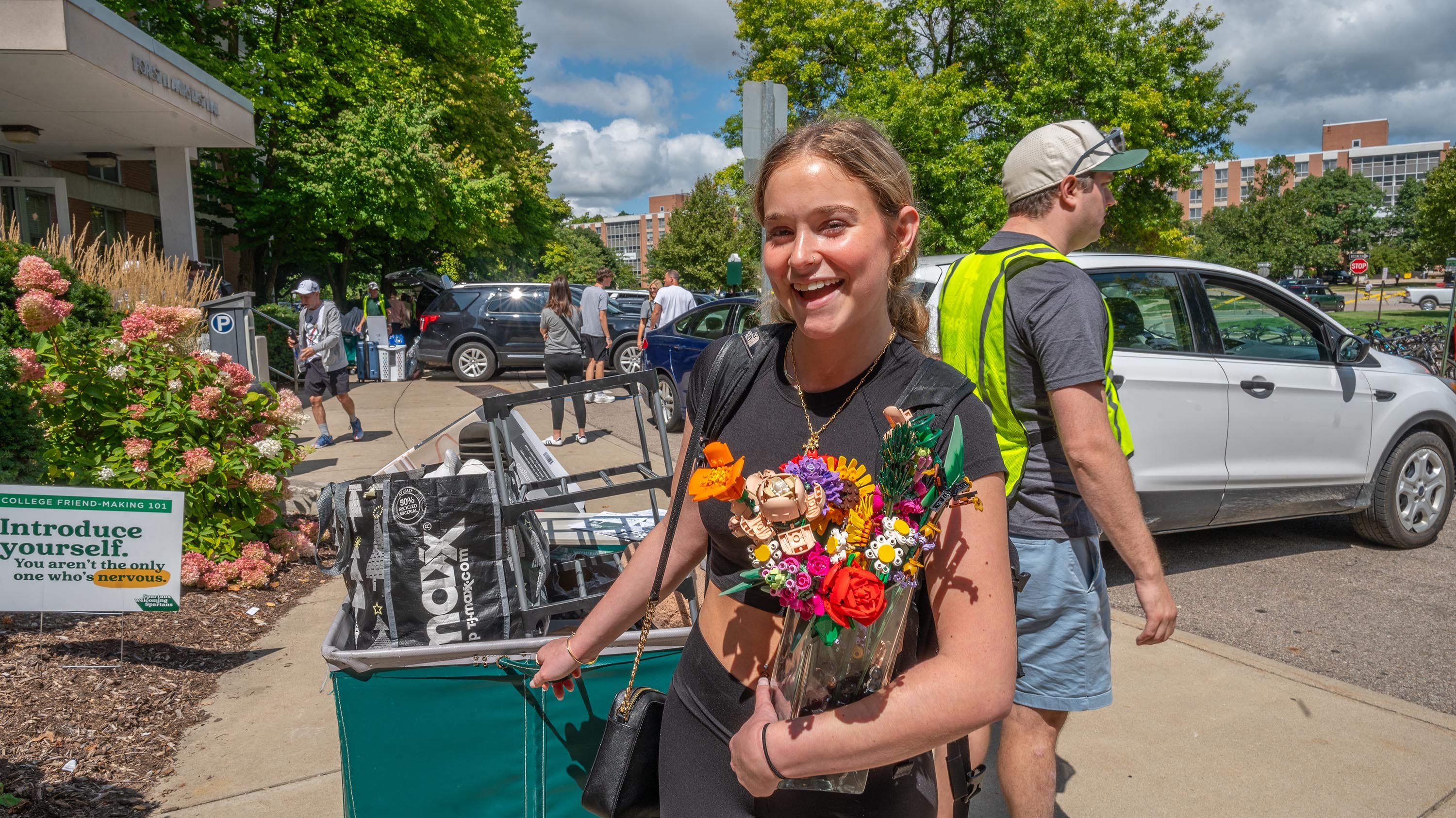Student with move-in laundry cart holding bouquet of toy flowers