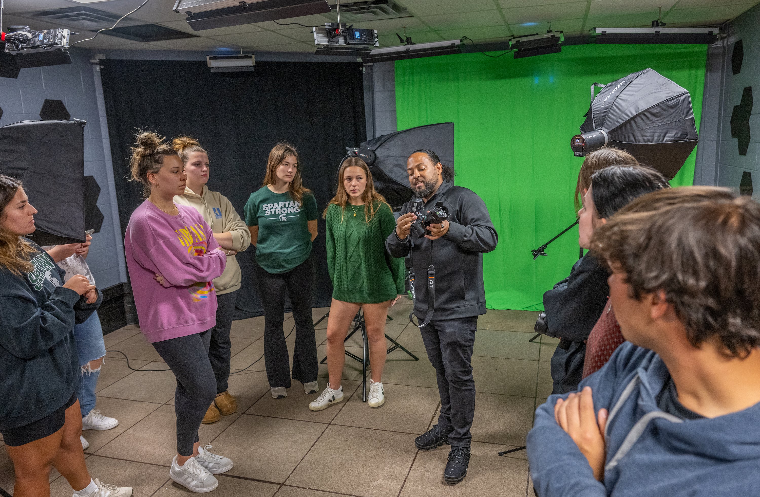 A group of students looks on as someone holds a camera.