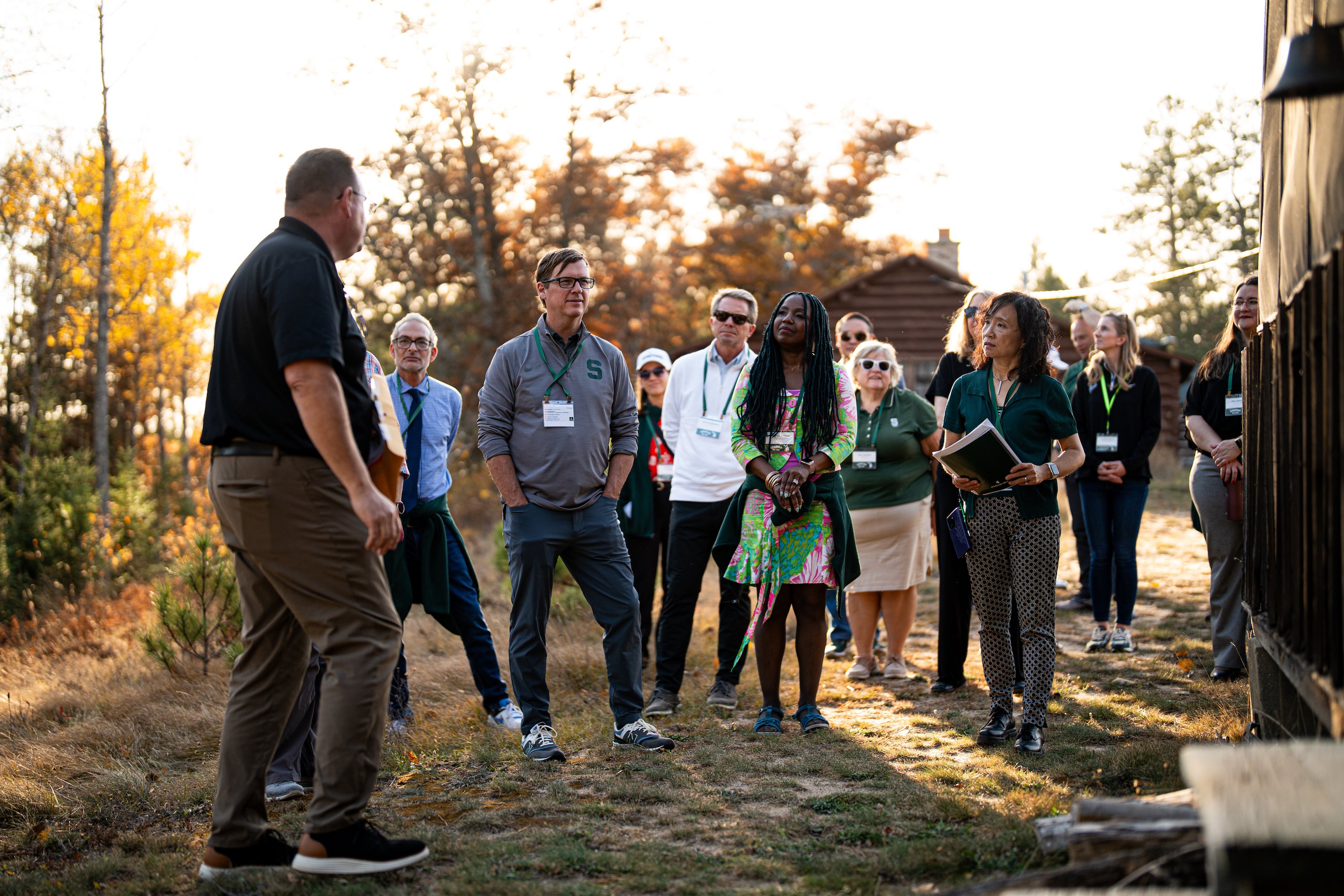 A group of people stand outside at MSU?s Camp Wa Wa Sum, a 144-year-old classic log cabin conference and research center located on the Au Sable River.