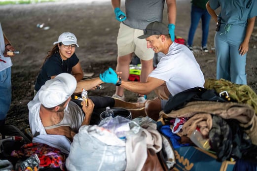 Two individuals help a third individual who is outside and needs care.