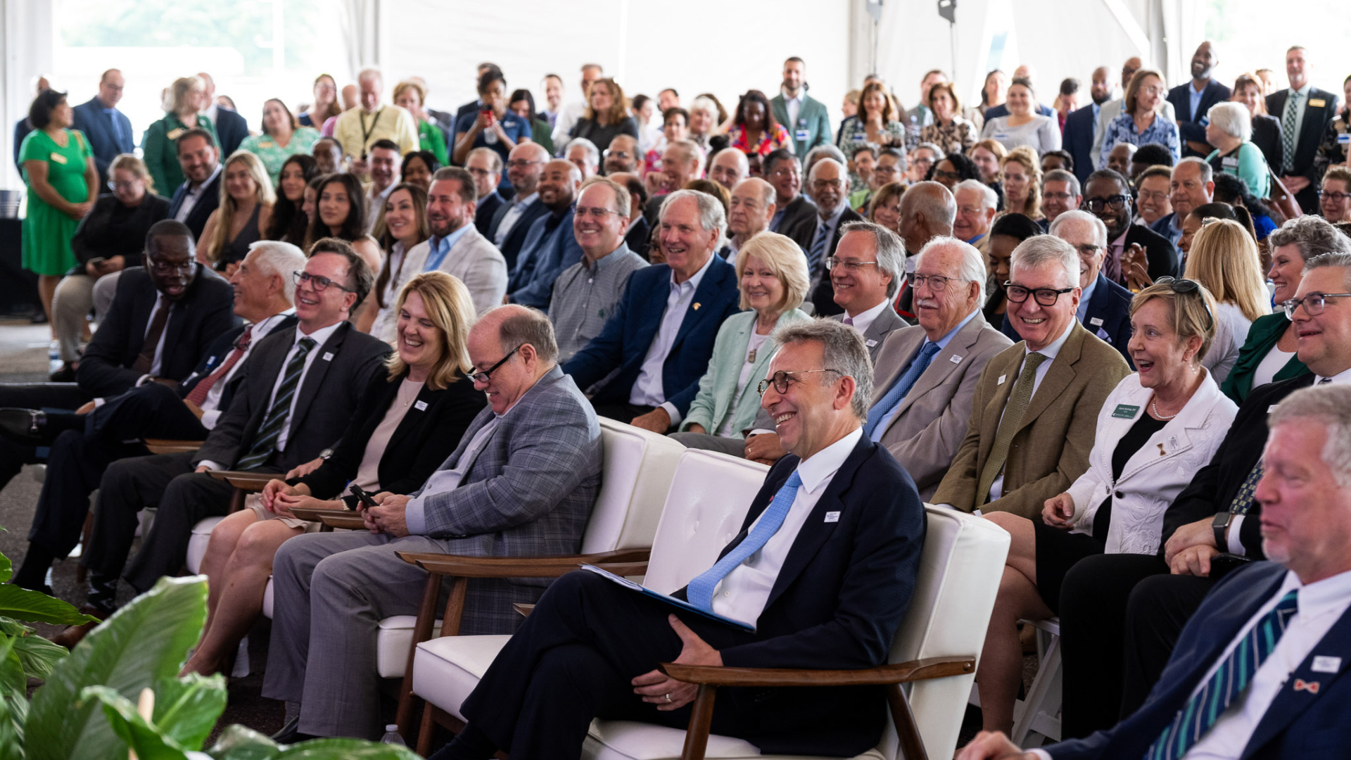 A large audience watches the proceedings at the groundbreaking ceremony, showing engagement and enthusiasm.
