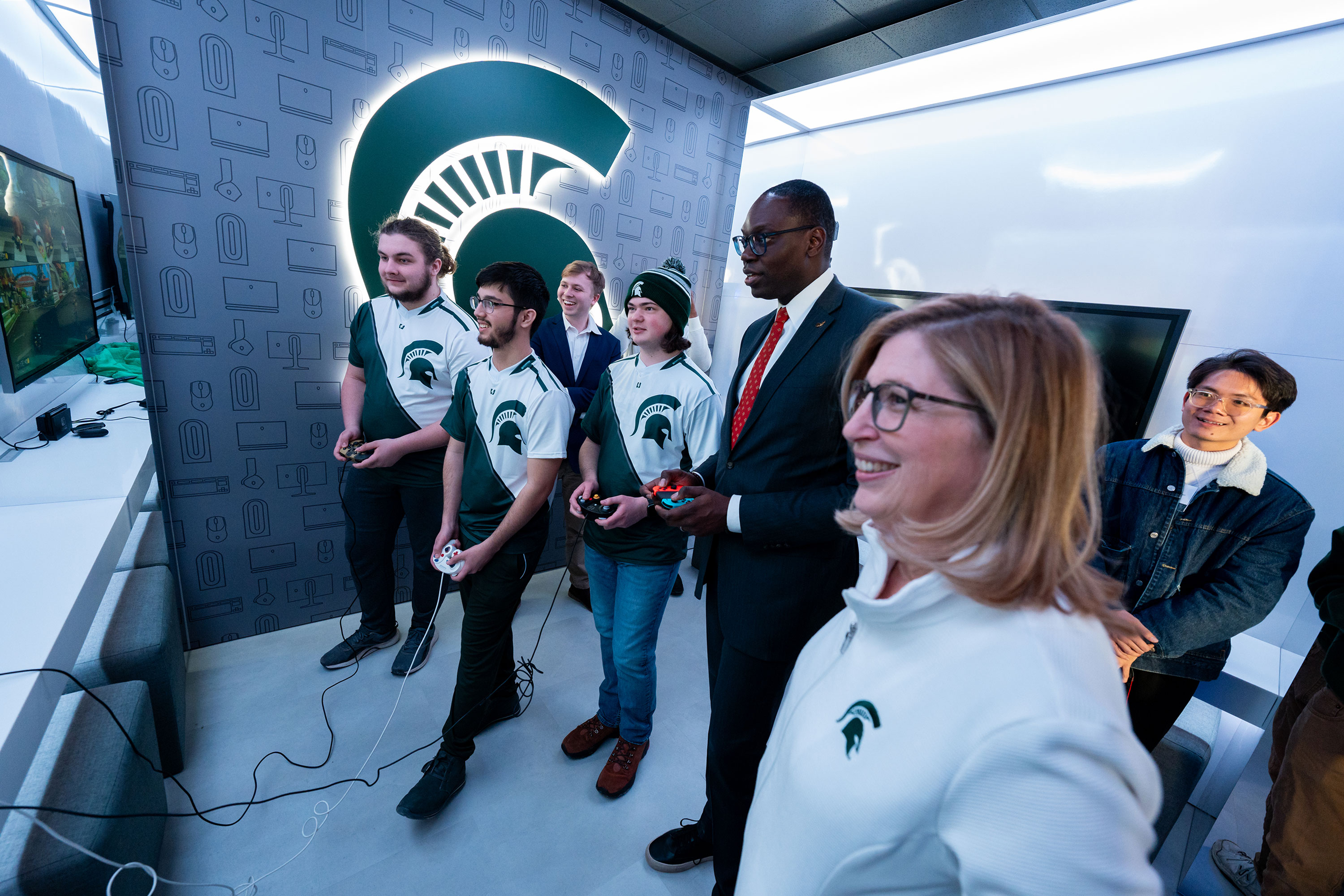 MSU Interim President Teresa K. Woodruff, Ph.D. and Michigan Lt. Gov Garlin Gilchrist II play a video game with members of the MSU esports team.