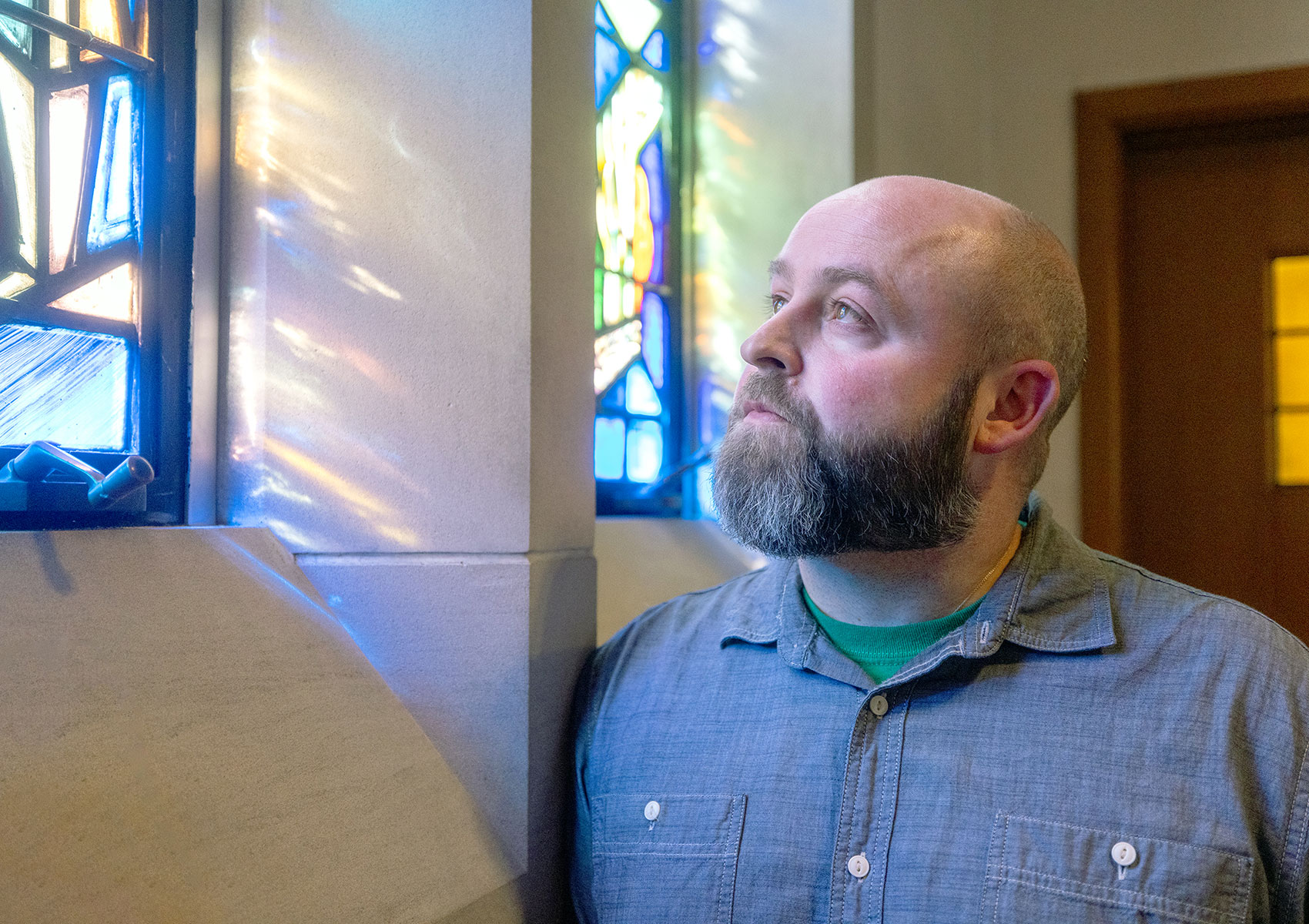 A man looking at a stained glass window.