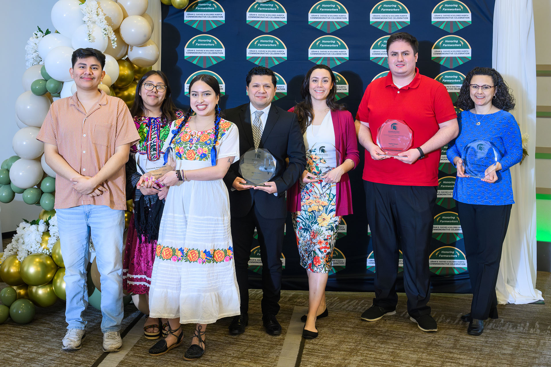 Award recipients hold plaques in front of a photo backdrop.