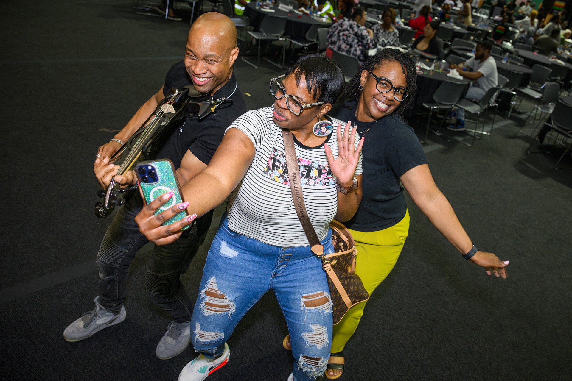 Rodney Page plays his violin while posing for a photo with people dancing 