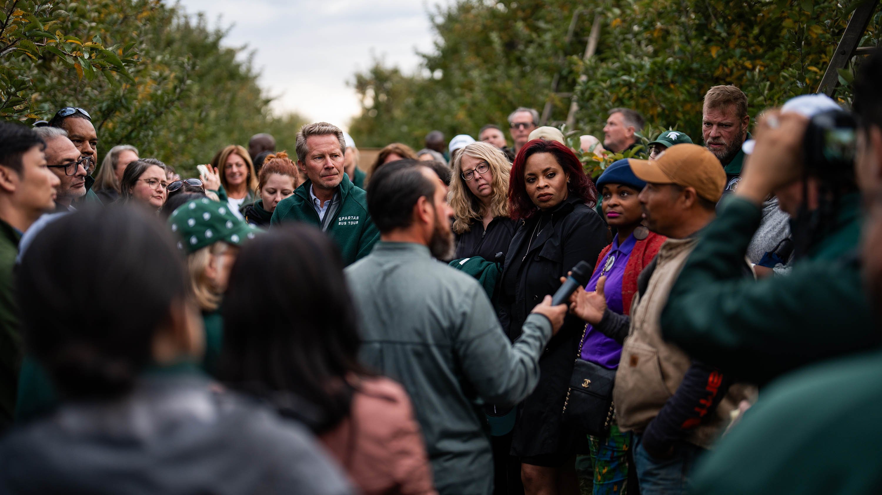 A group of people pose for a photo in an apple orchard. 