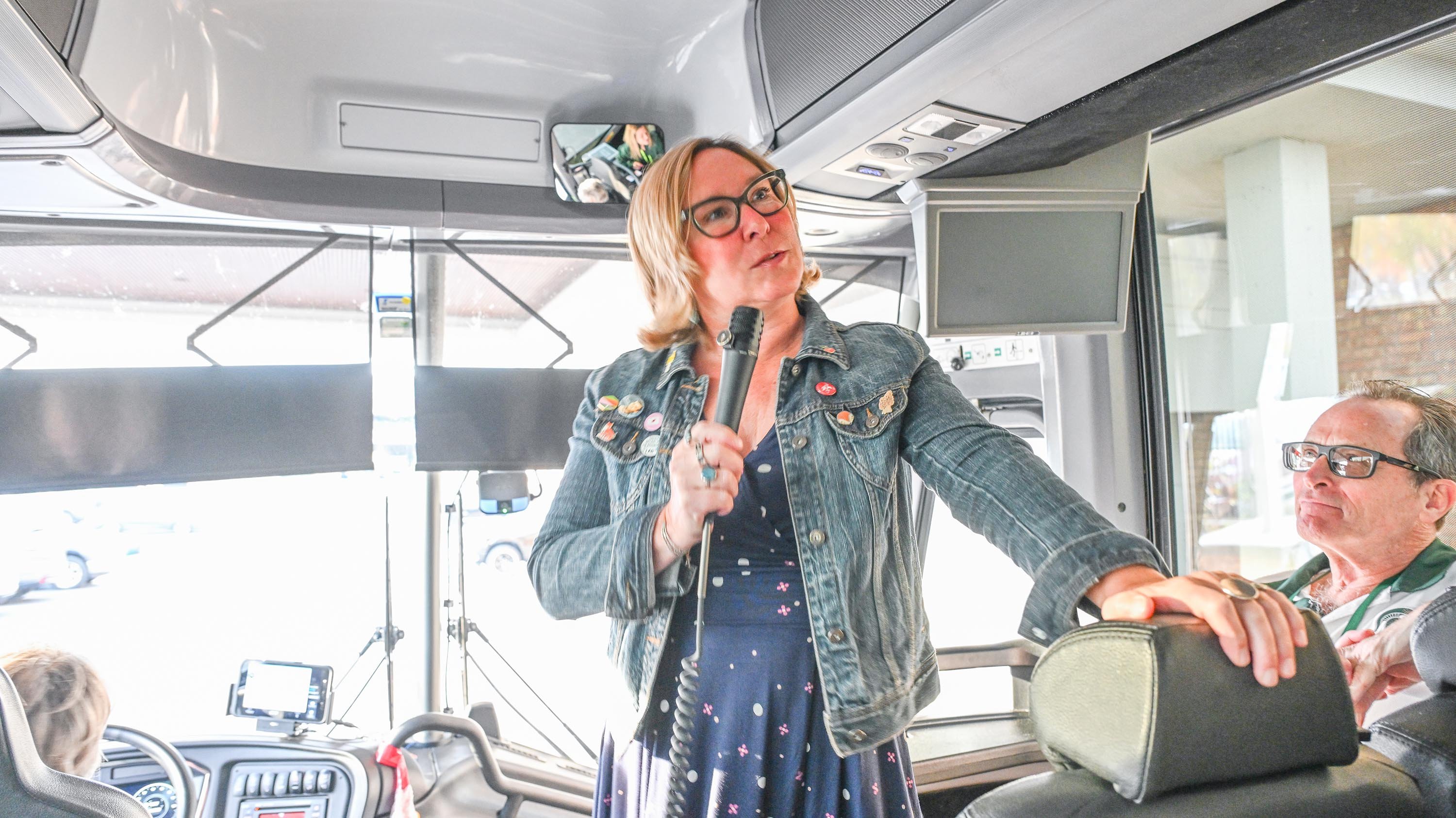 A woman talking on a speaker on a bus.