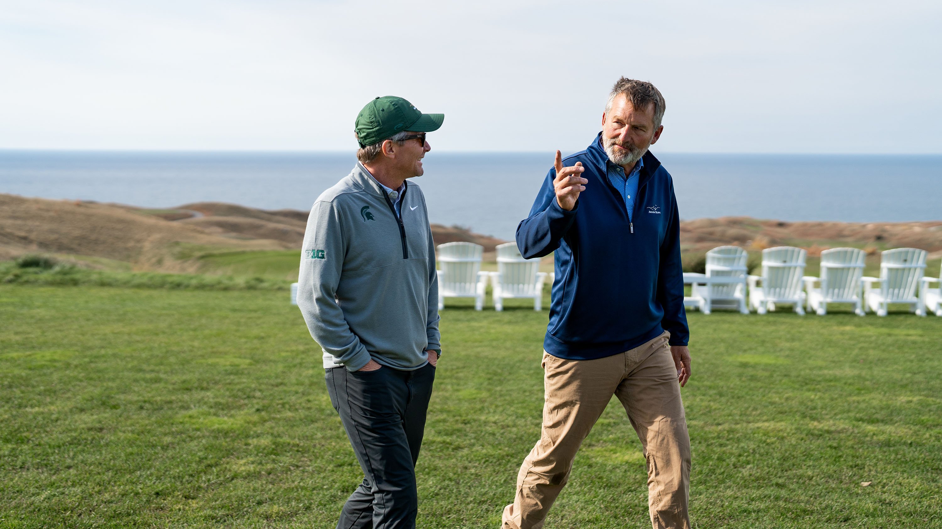 Two men walking on a golf course. Lake Michigan is behind them.