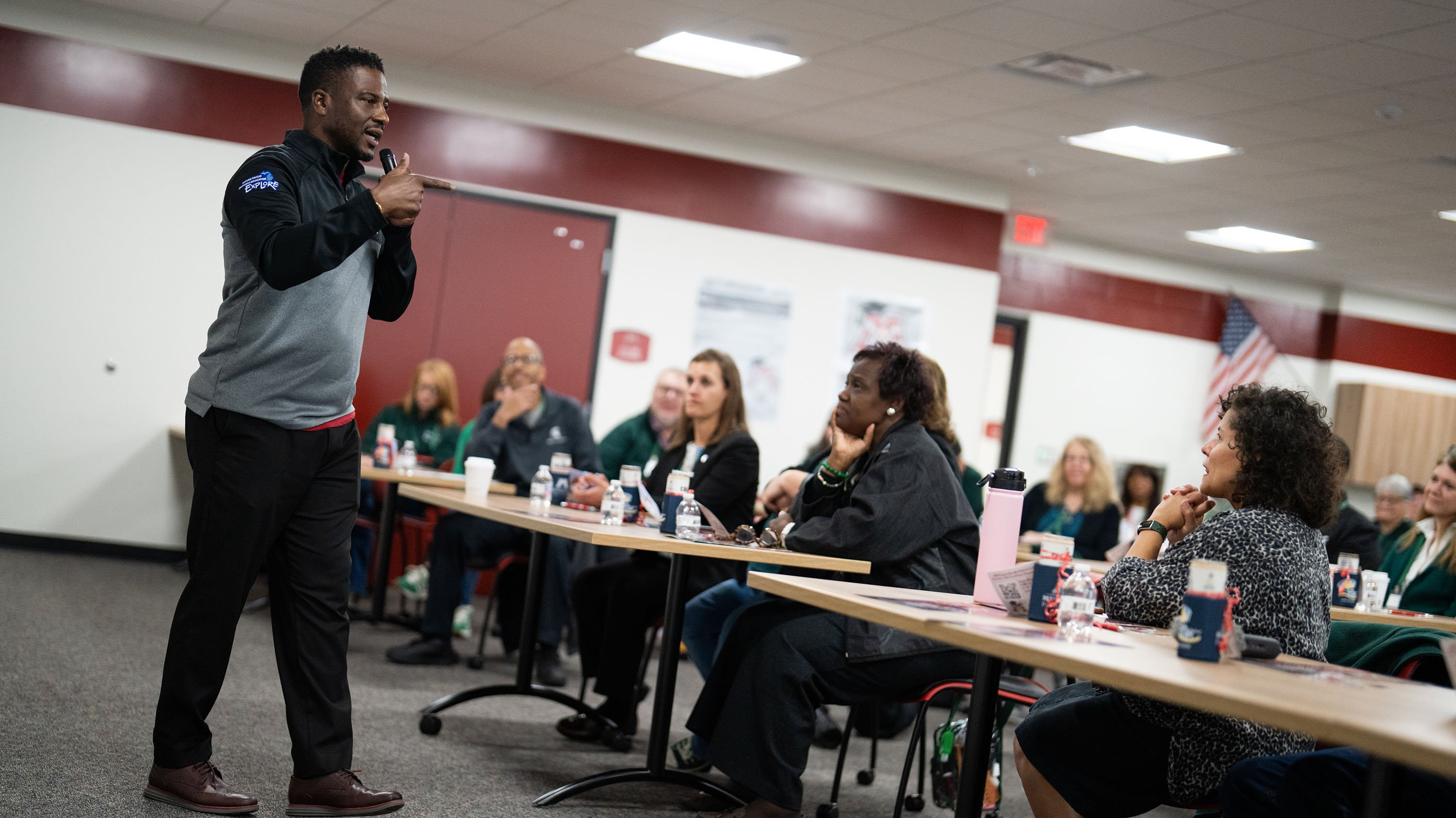 A person presenting in front of people sitting at tables.
