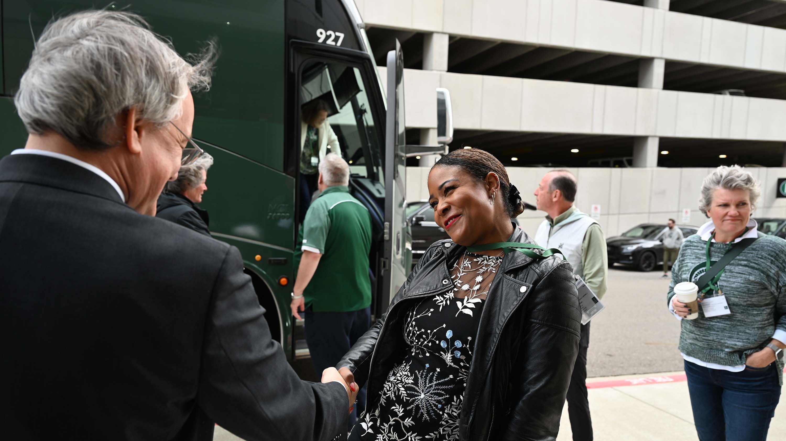 A person smiles while shaking hands with another person.