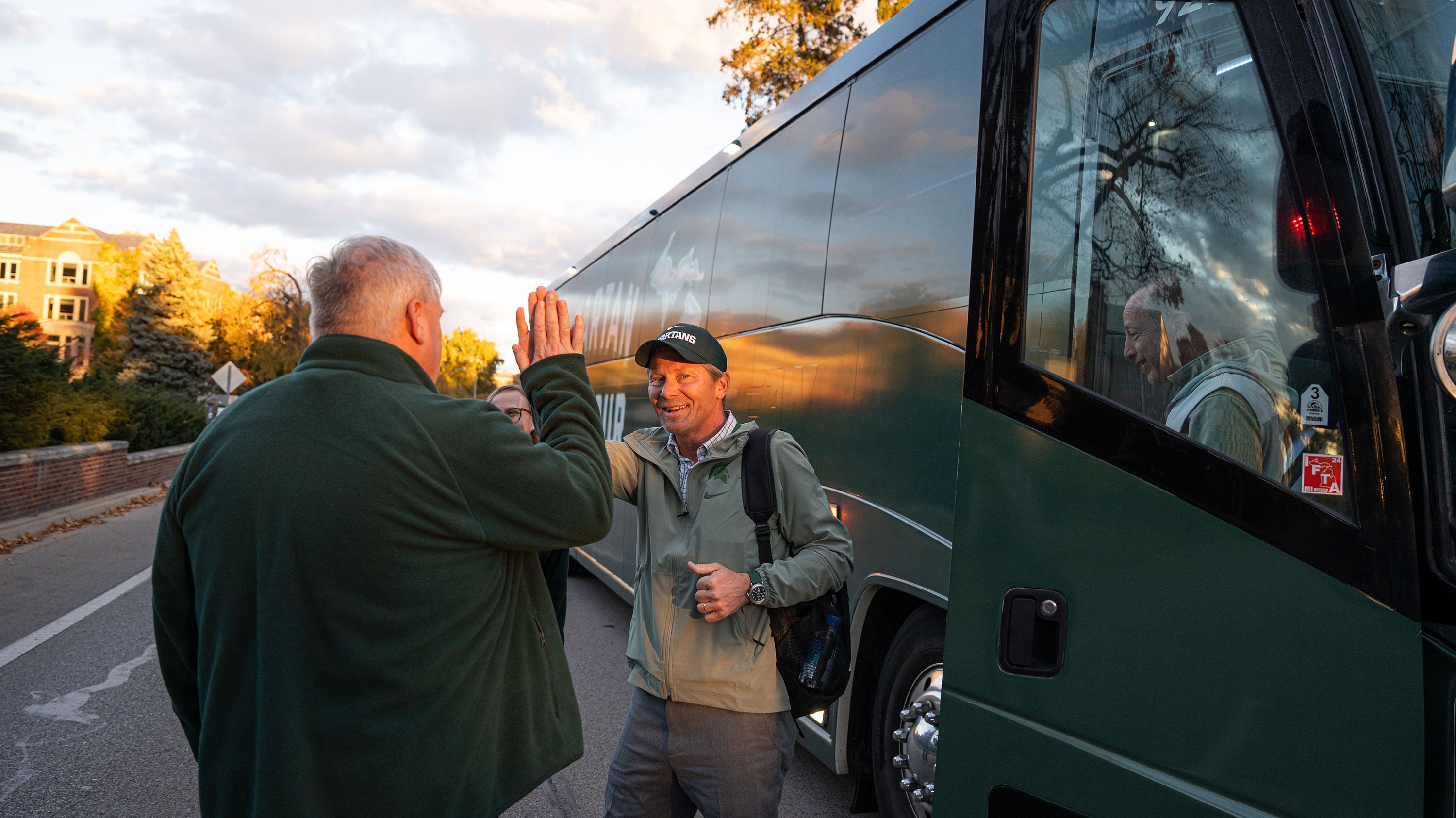 A person high-fiving another person while exiting a bus.