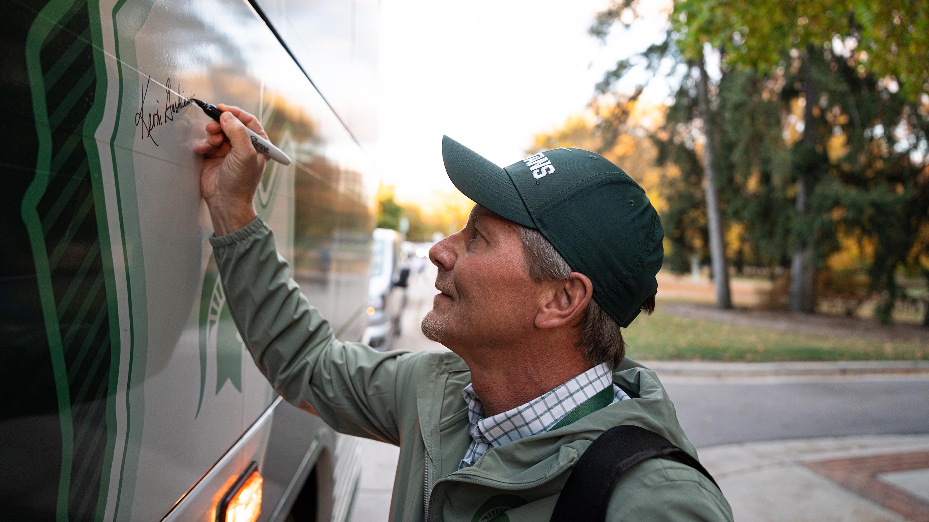 A person signing a bus with black marker.