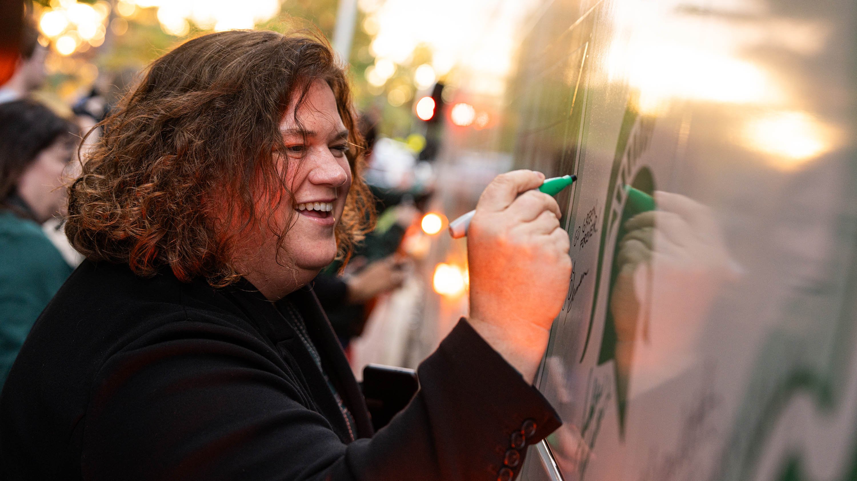 A person signing a bus with a green marker.