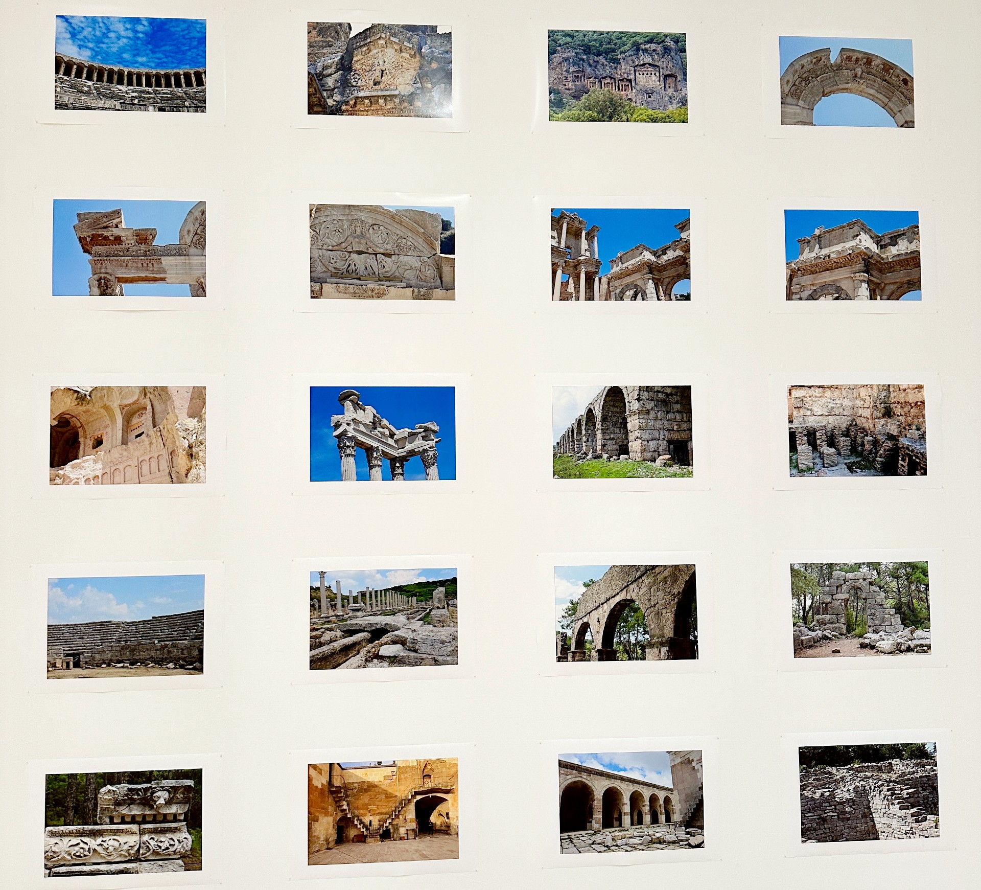 A grid of photographs of ancient architecture are mounted on a wall.