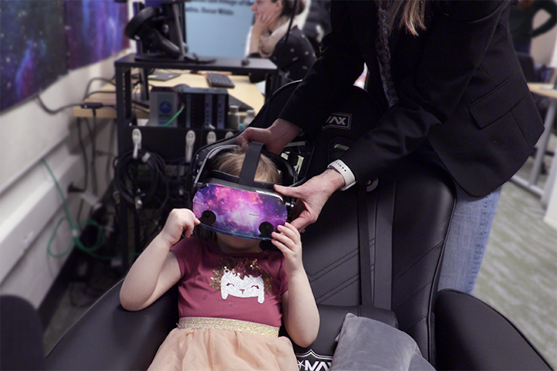 An adult helps a child put on a virtual reality headset.