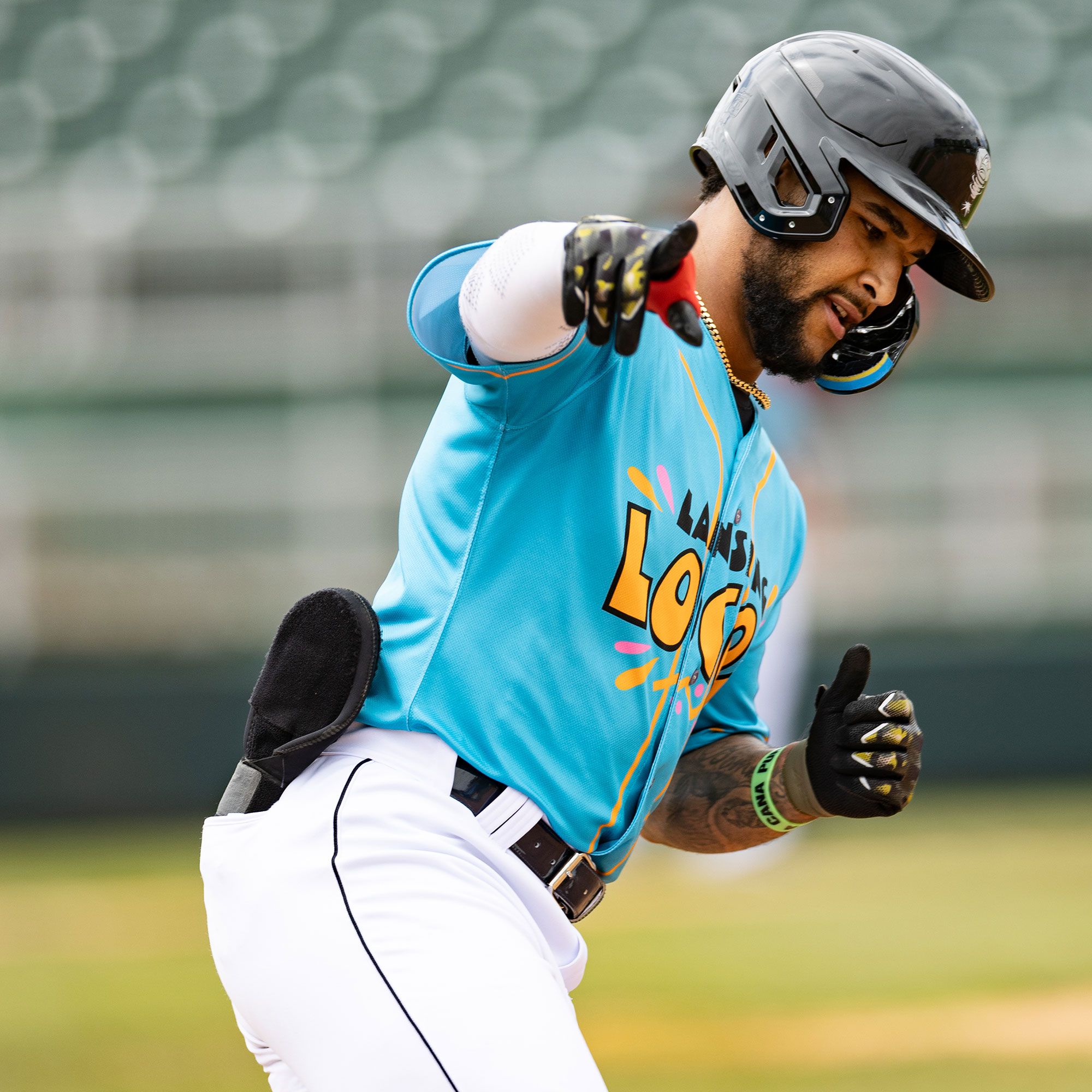 Baseball player holding up his hands and pointing while running the bases