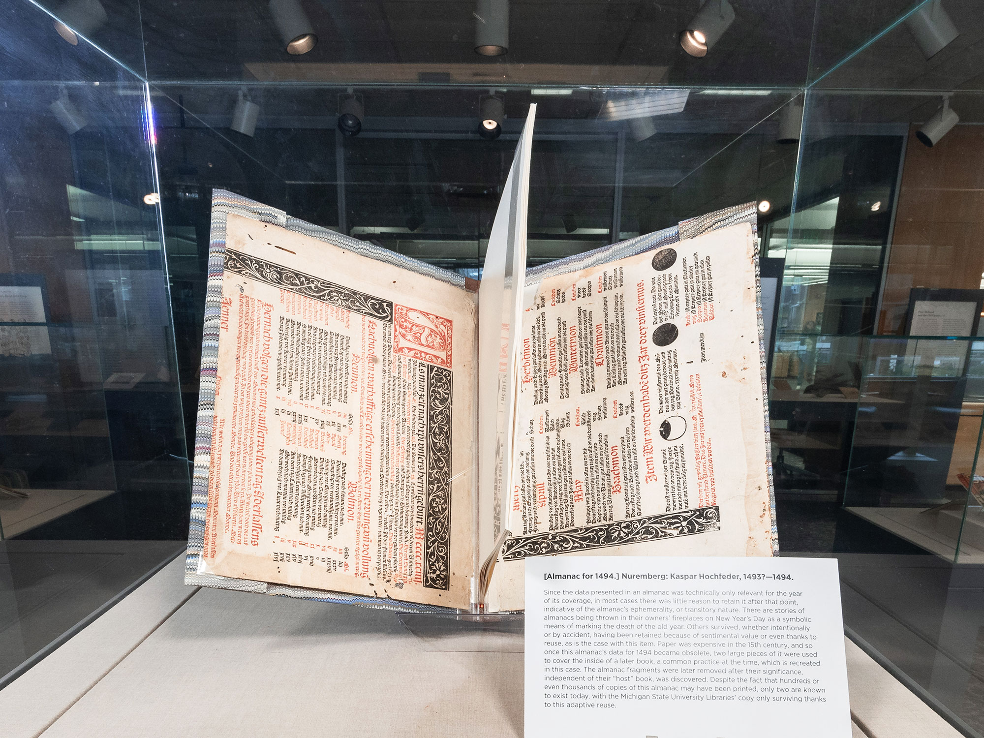 Book pages in a plastic protector. The pages are bound together and housed in a glass case.