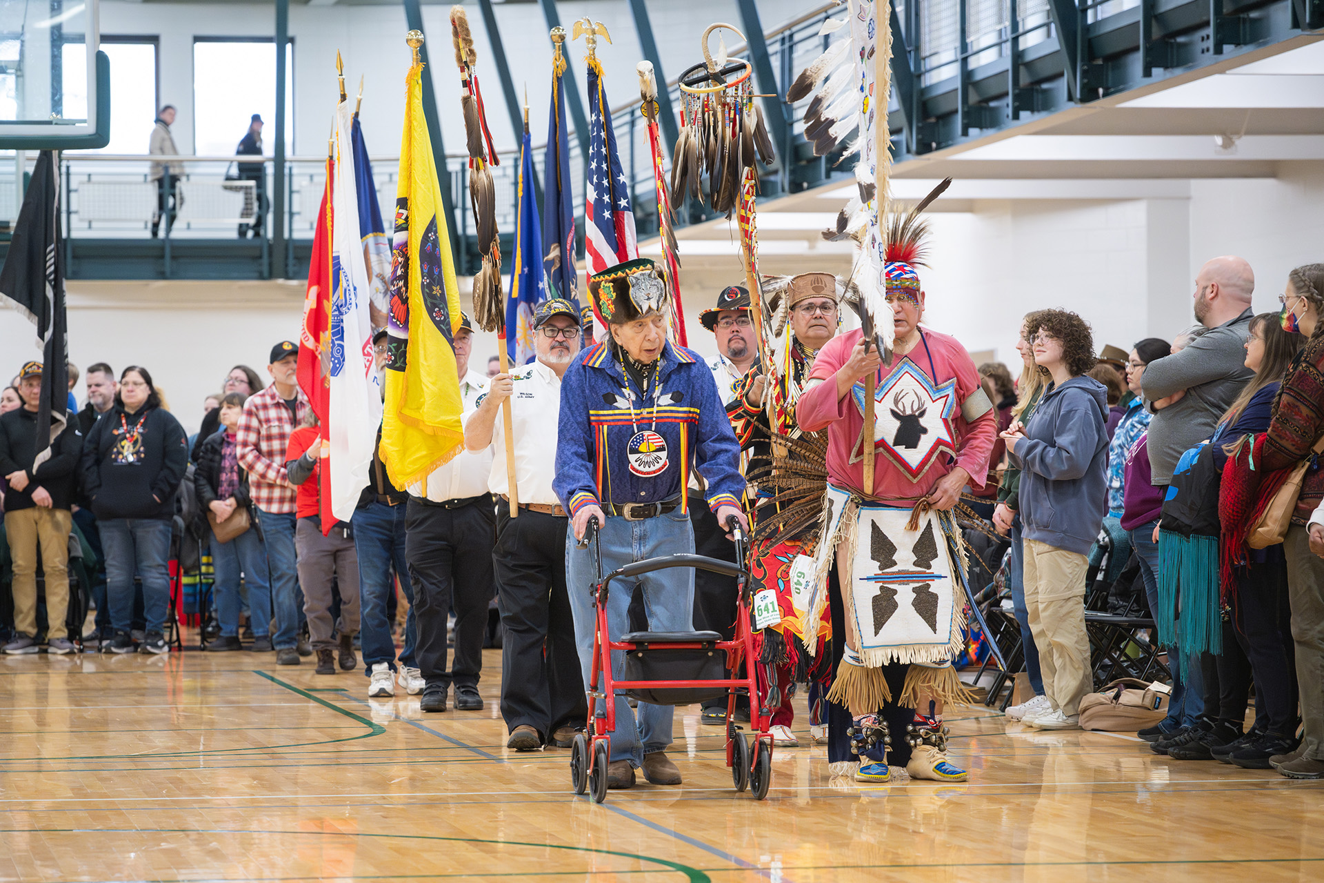 Powwow veteran dancers move in line carrying flags