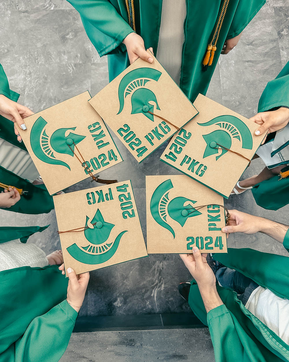 Five graduation caps with Spartan helmet and PKG'24 decoration