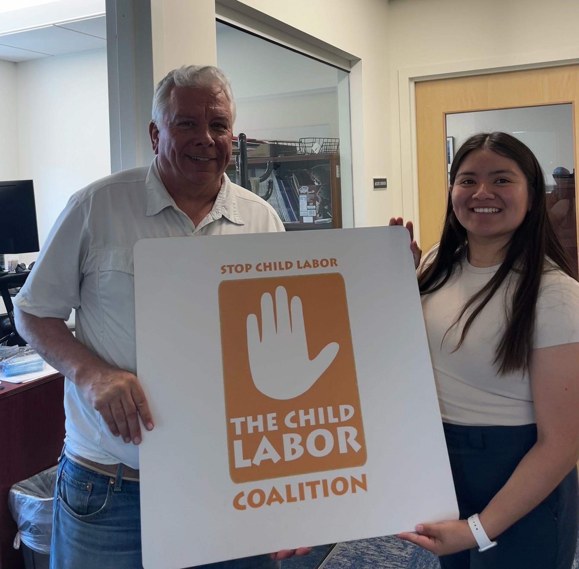 student intern holds a sign with supervisor in office