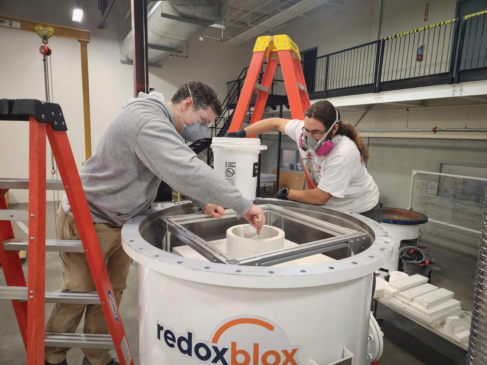 Individuals from the startup Redoxblox work on a piece of energy-storage equipment.