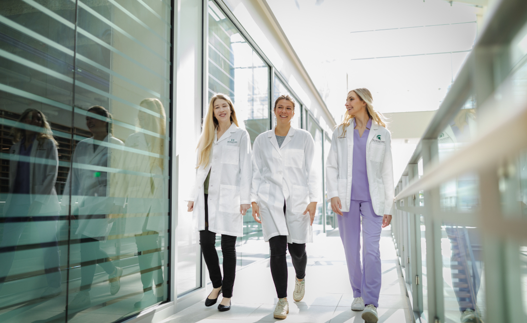 Students in the College of Human Medicine walk through a modern corridor, symbolizing the future of women's health research supported by the Walstrom Family Endowed Women?s Health Research Fund.