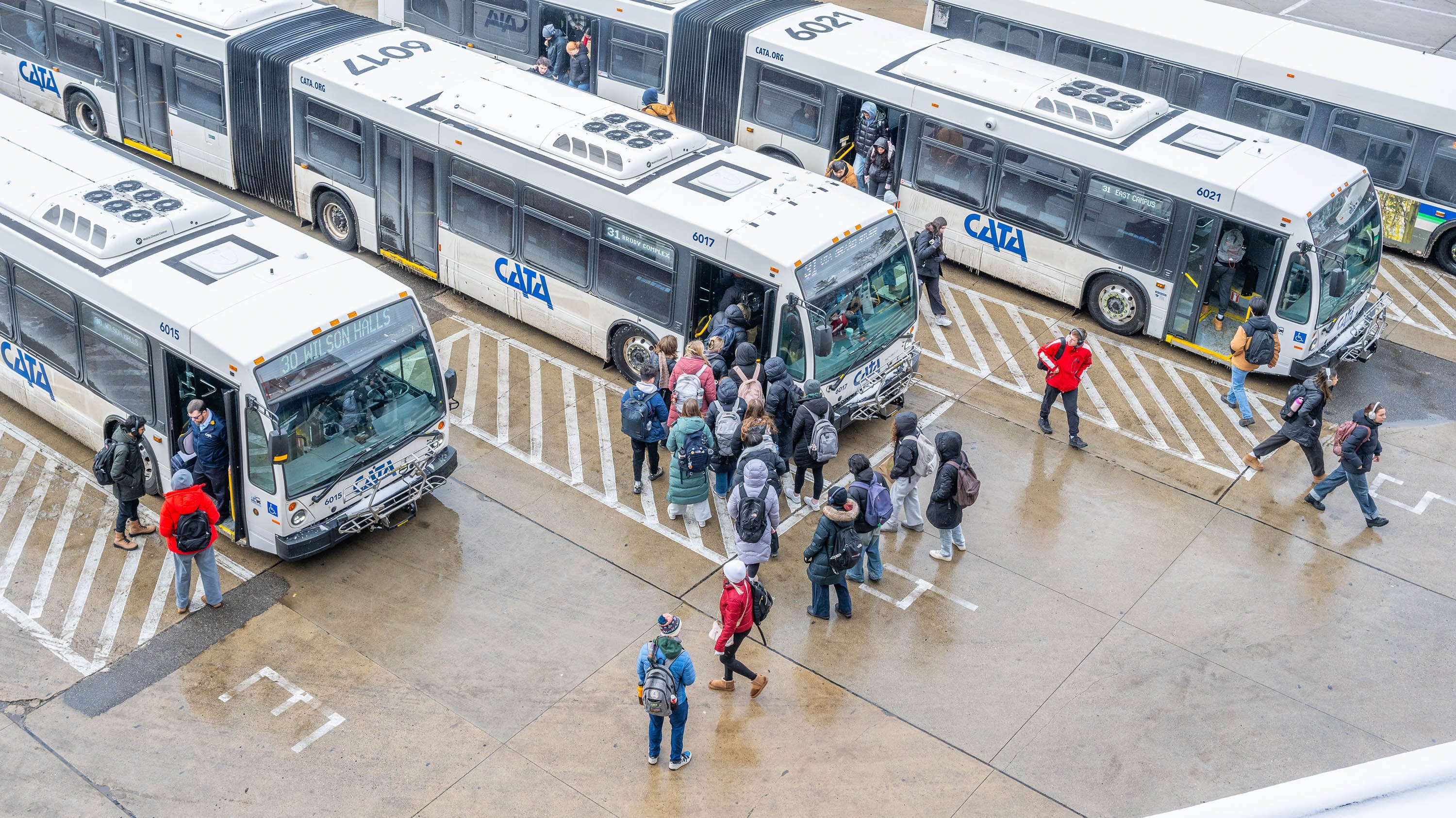 People entering buses at a terminal