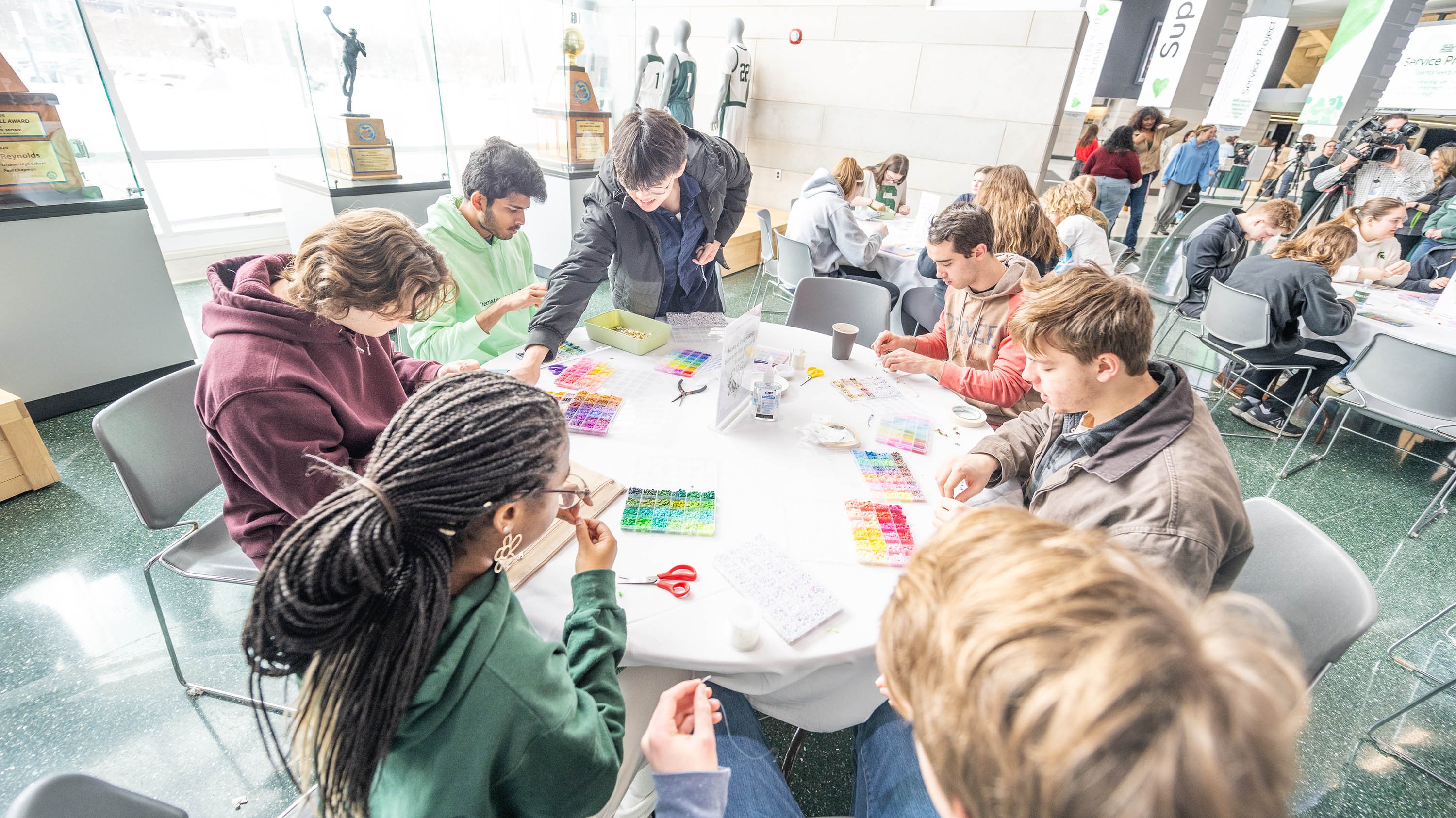Students around a table making friendship bracelets 