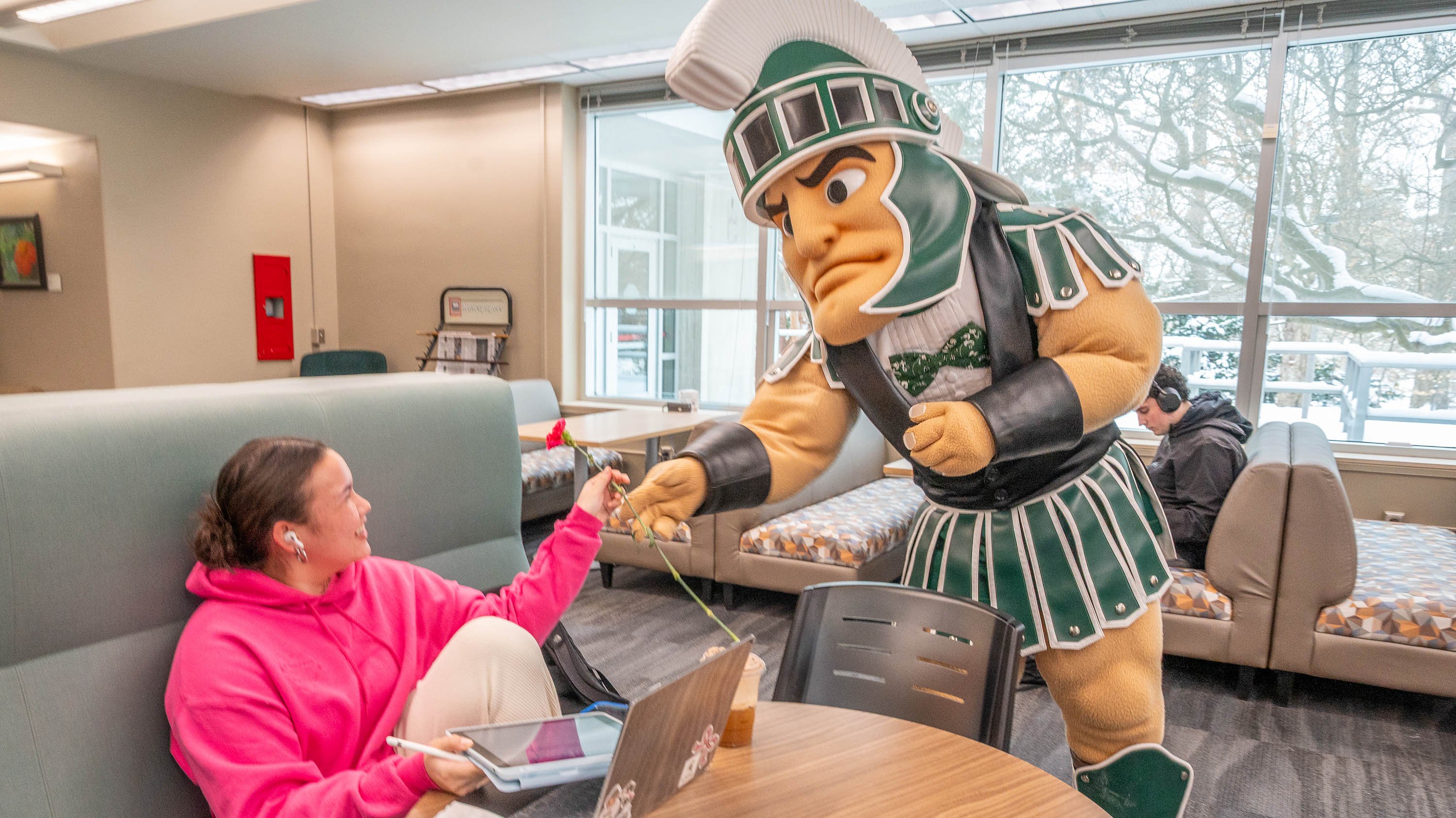 Sparty handing a student a flower