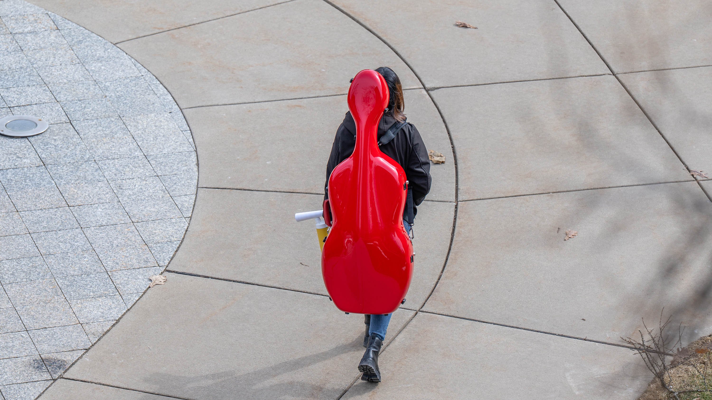 Person with a red cello case walking through Hannah Plaza