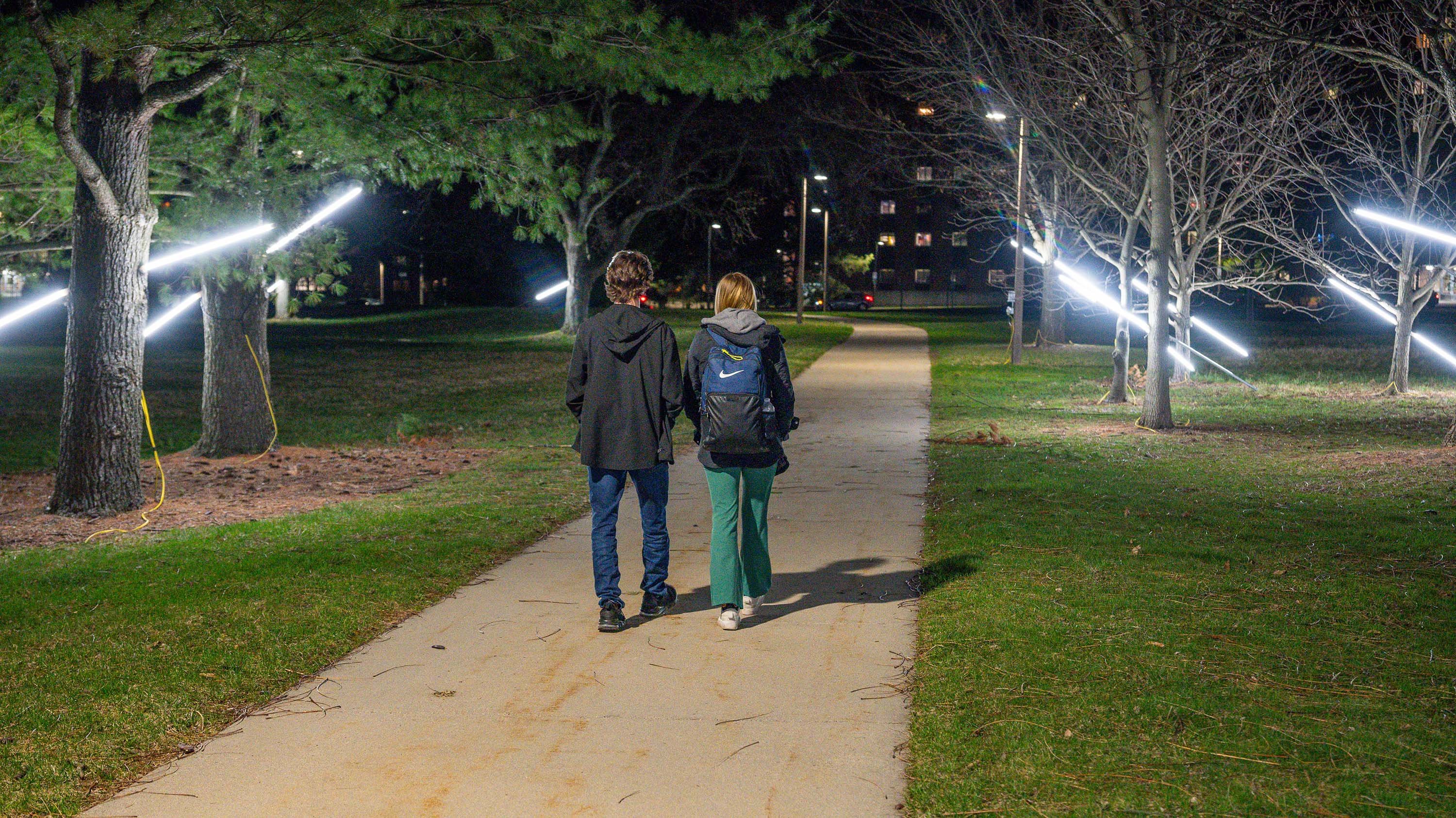 Two people walking past an art installation