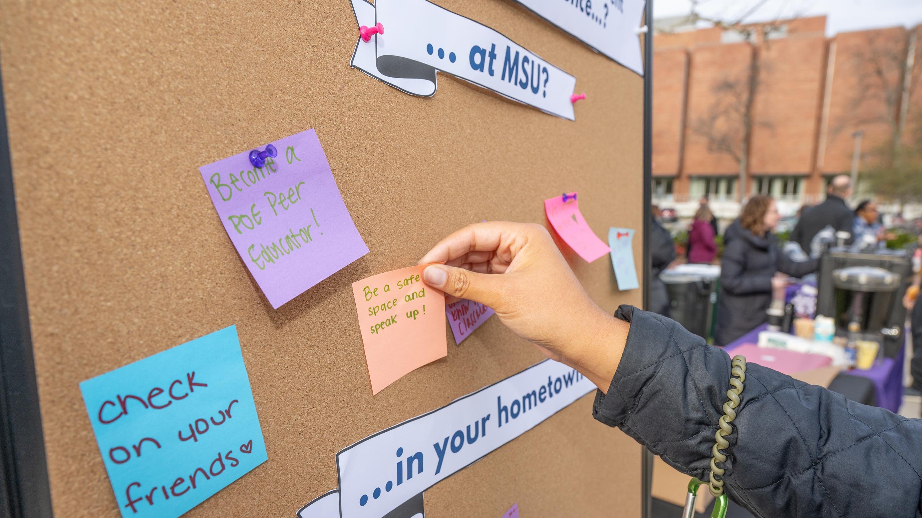 Person adhering sticky note to a board
