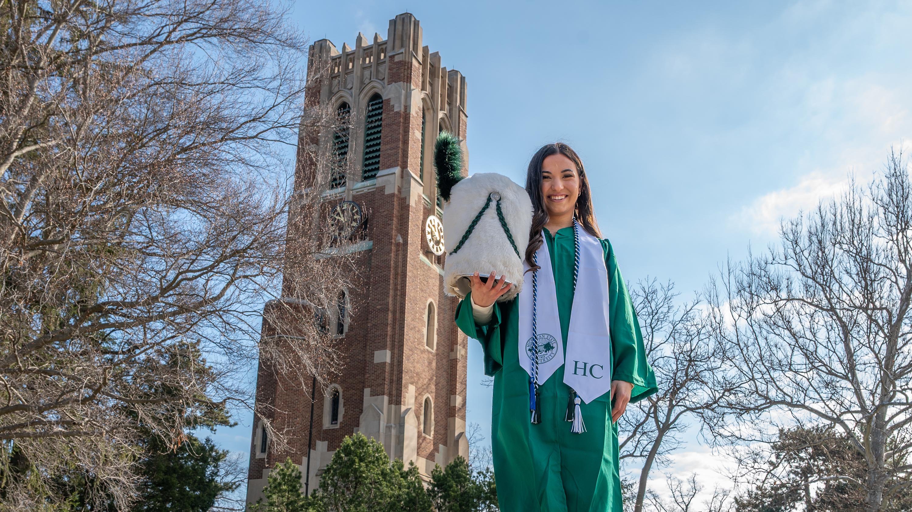 Lacy Jewell wearing graduation gown and holding drum major hat