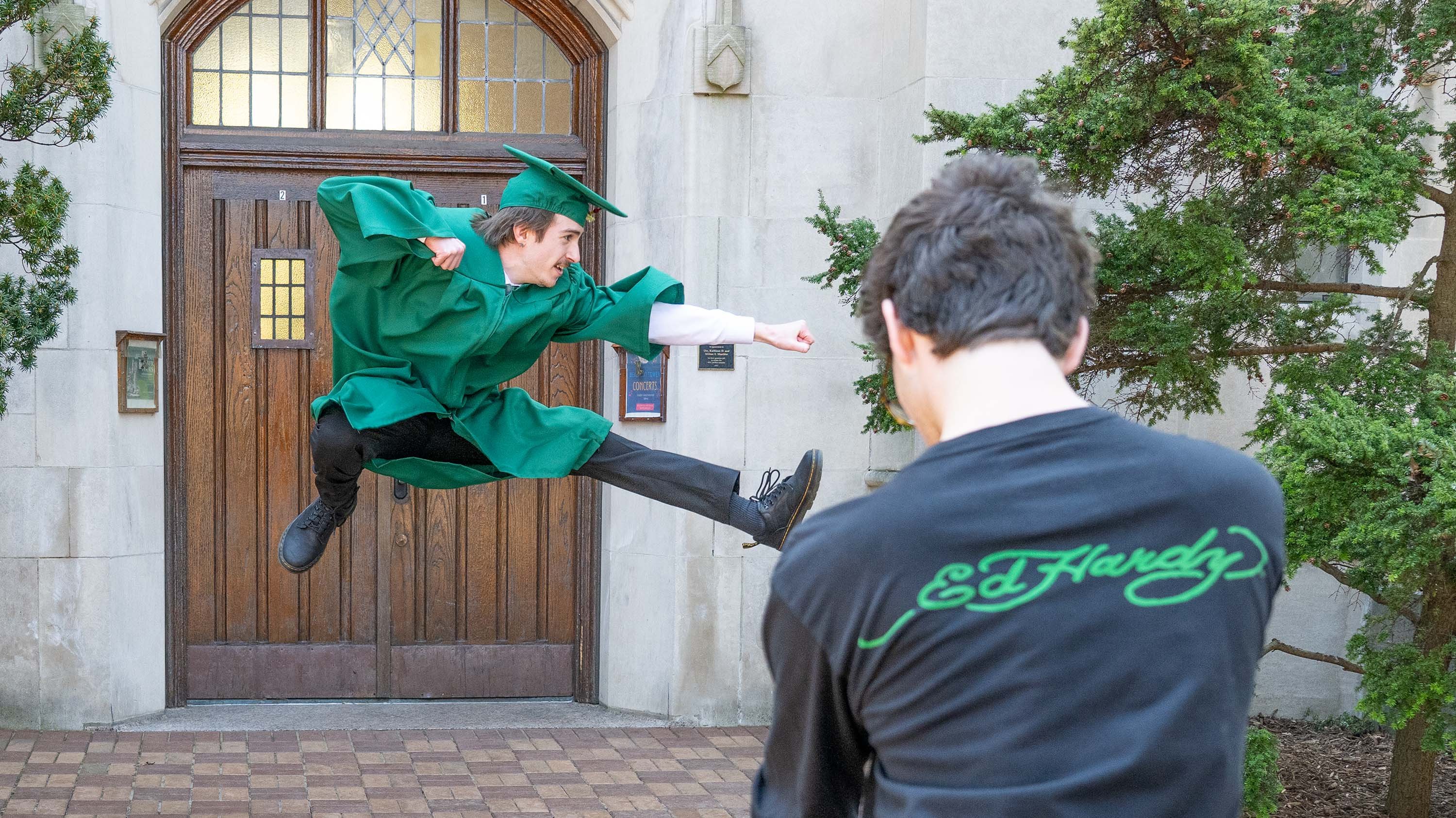 Student doing a martial arts pose while jumping for a graduation photo