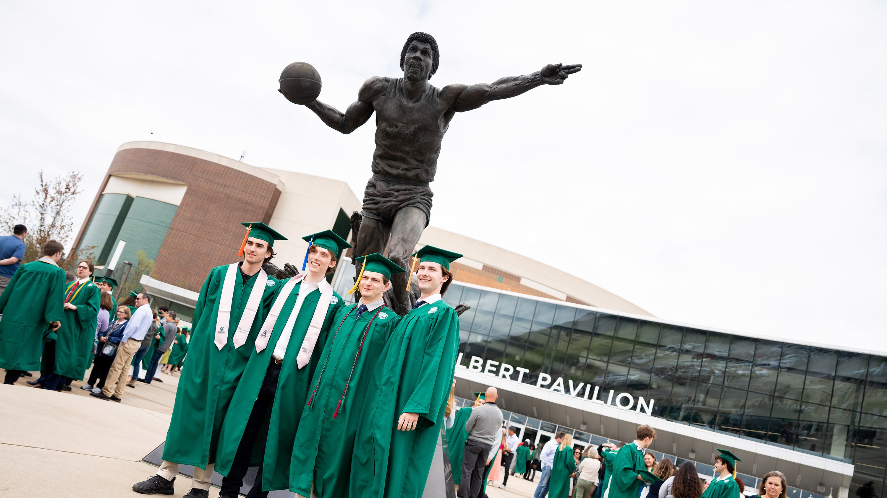 Graduates posing for picture in front of Magic Johnson statue